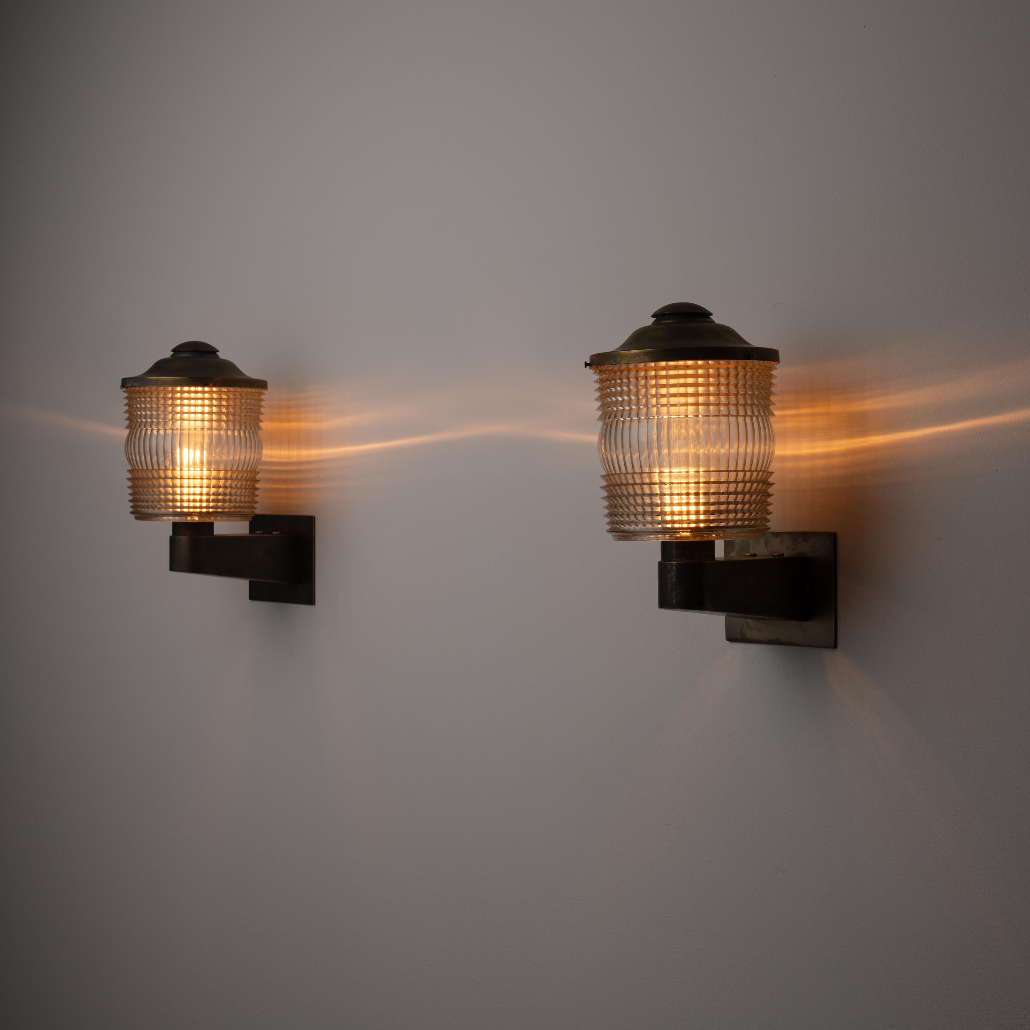 Pair of Sconces by Atelier Jean Perzel. Designed and manufactured in France, circa 1940. Industrial, lantern-like wall sconces with sturdy brass frame and custom textured glass diffusers. Each sconce holds two E27 sockets, adapted for the US. We