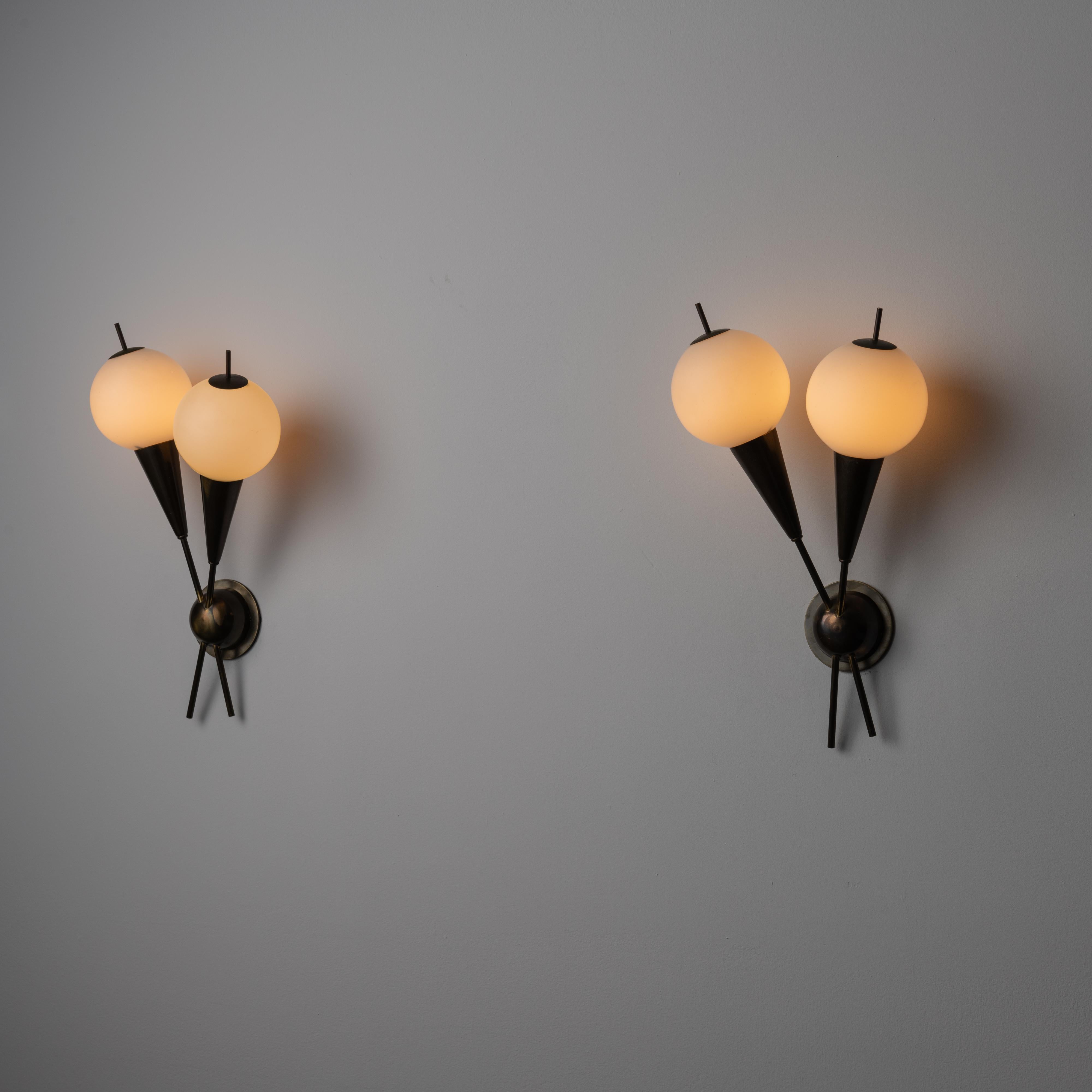 A pair of sconces by G.C.M.E. Designed and manufactured in Italy, circa the 1960s. A pair of sconces with nicely accented outer glass finials. Each sconce consists of two glass globes and armatures, criss-crossing over each other. Each globe houses
