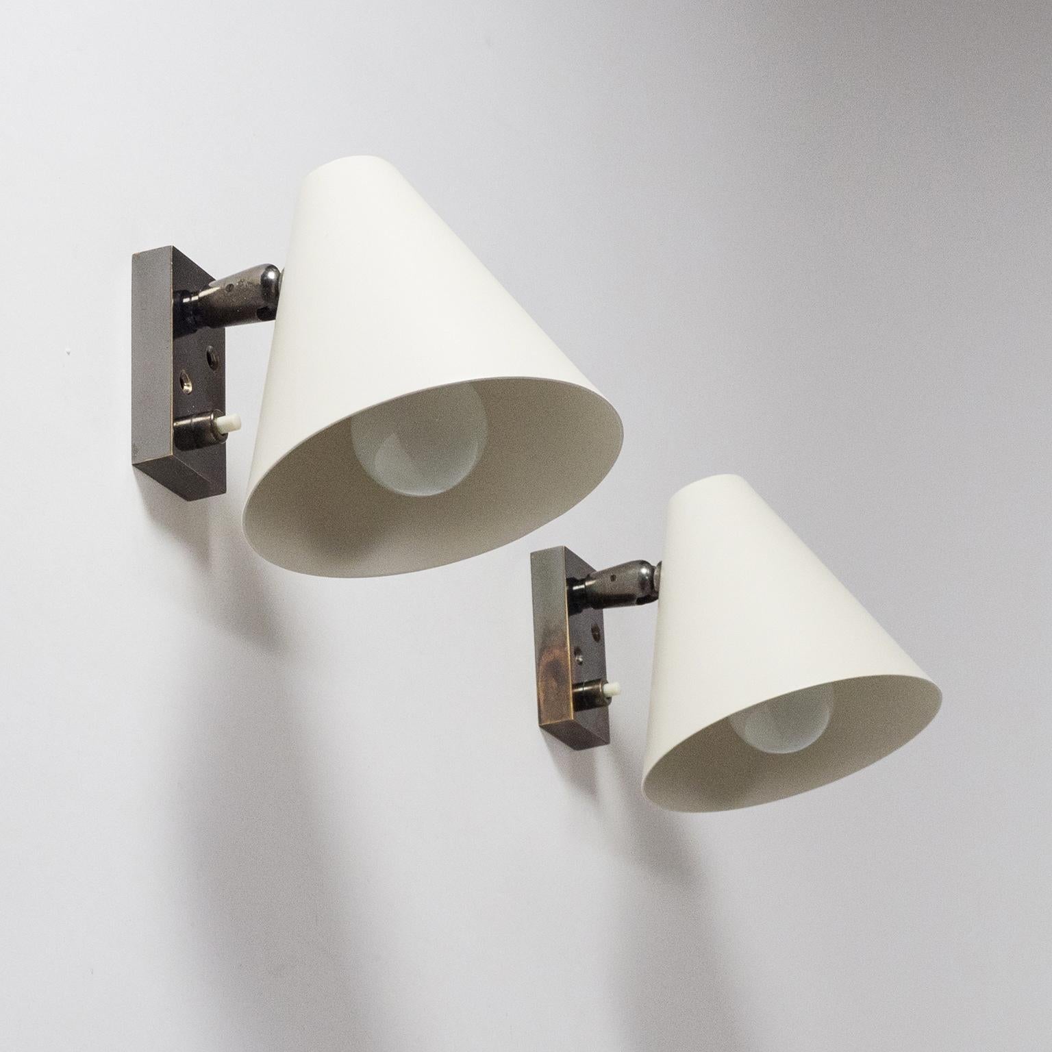 Rare pair of modernist sconces attributed to Giuseppe Ostuni for Oluce. The brass hardware is patinated in a dark silvery hueand the he aluminum shades are lacquered in a matte off-white. Can be rotated almost entire 360 degrees. One original E14