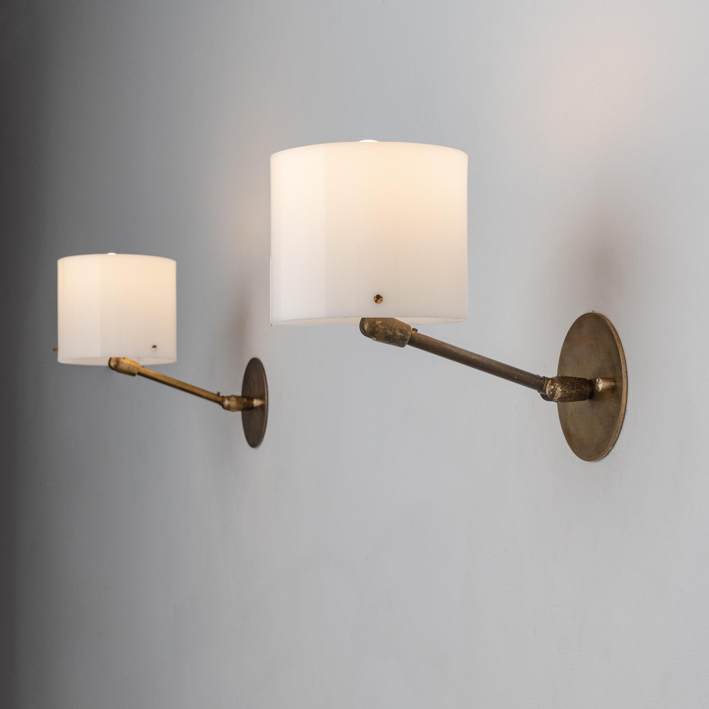 Pair of sconces by Giuseppe Ostuni for Oluce. Designed and manufactured in Italy, circa 1950's. Acrylic, brass, adjustable shade rewired for U.S. standards. Custom brass backplate. We recommend one E14 60w maximum bulb per sconce. Bulbs not included.