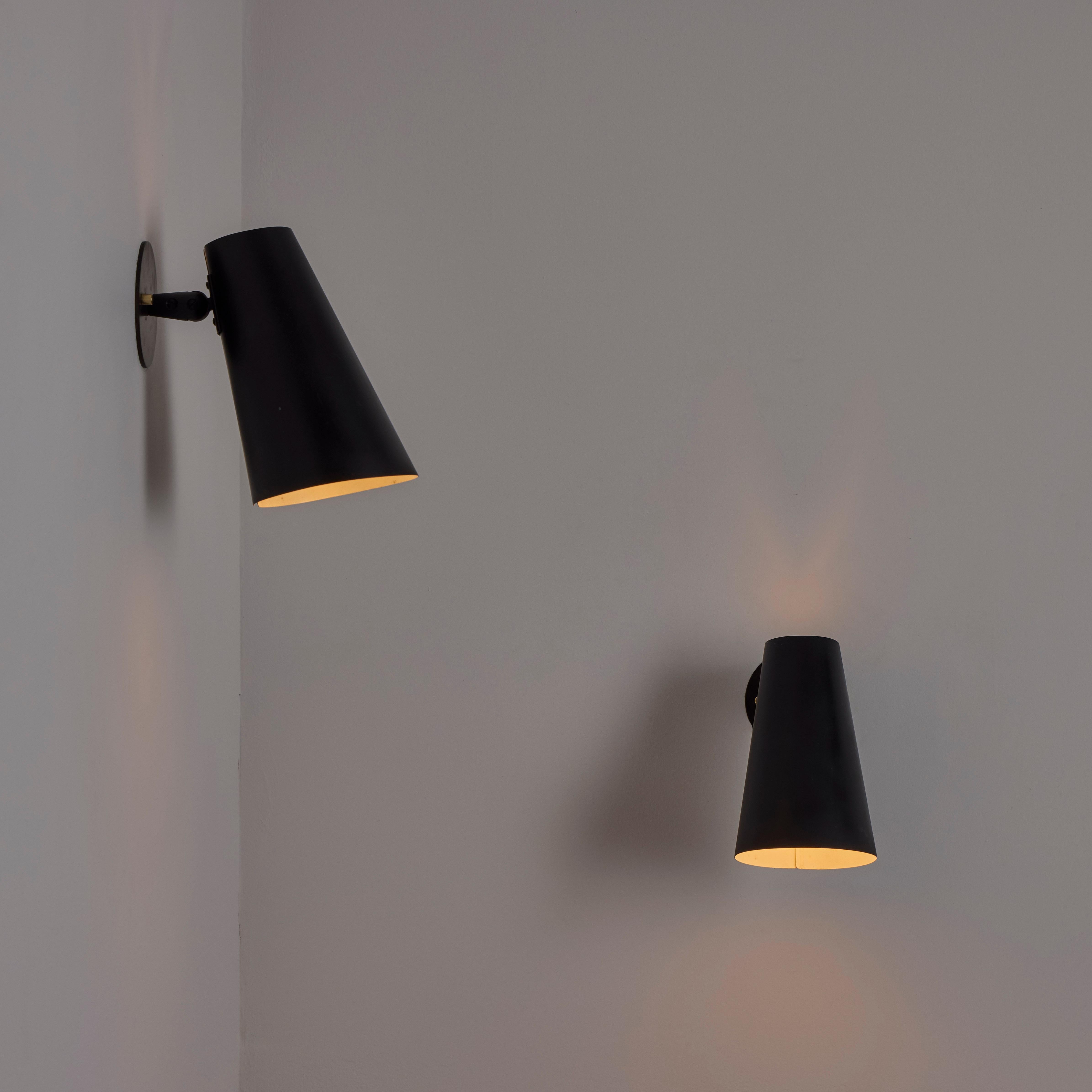 Pair of Sconces by Giuseppe Ostuni for Oluce. Designed and manufactured in the 1960s. Black enameled shades with blackened brass details. Each sconce holds a single E27 socket-type, adapted for the US. We recommend a 40-60w max bulb or LED