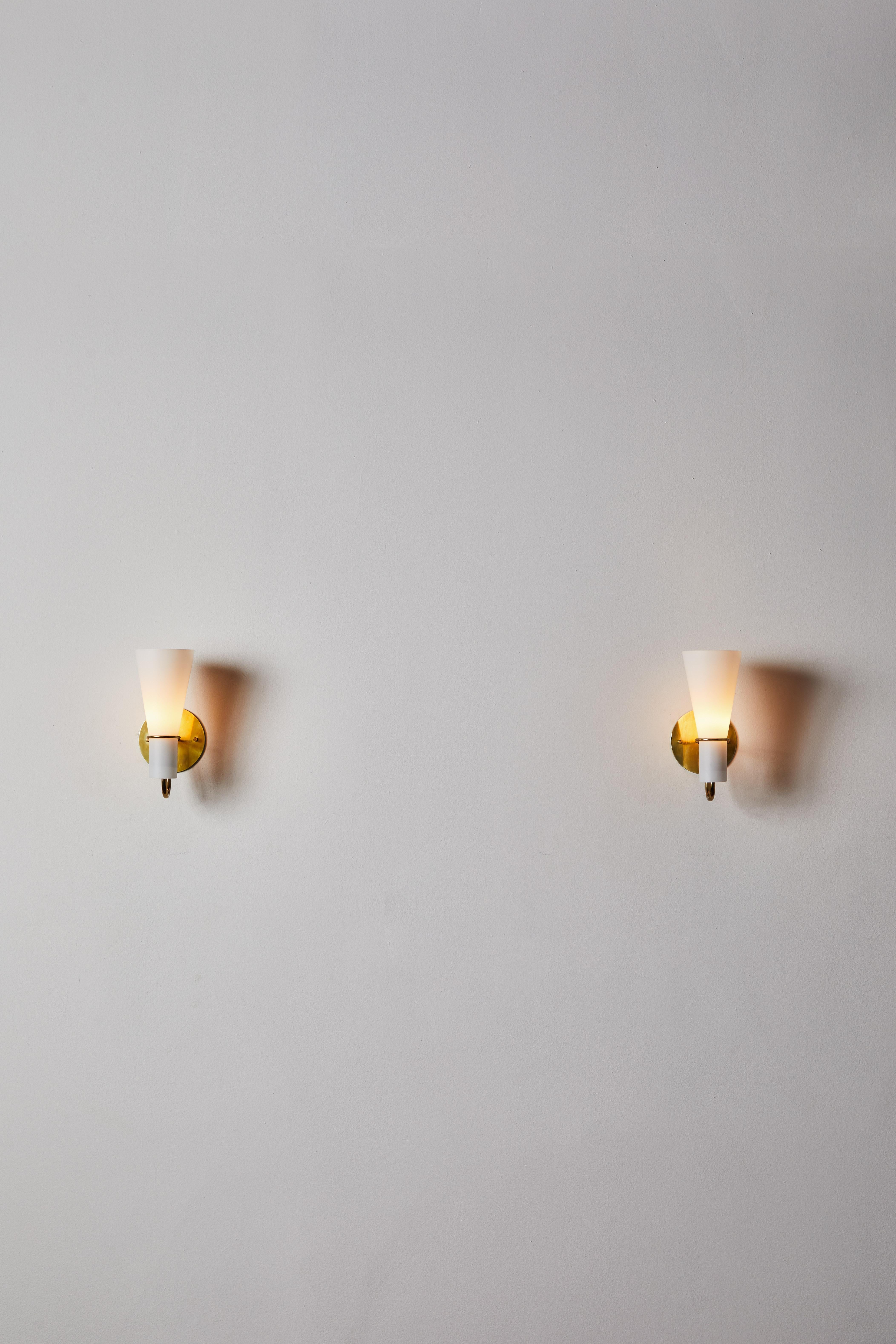 Pair of sconces by Hans Bergström. Designed and manufactured in Sweden, circa 1950s. Brushed satin glass diffuser, brass hardware. Custom brass backplates. Rewired for U.S. standards.
We recommend one E14 60w maximum European candelabra bulbs per