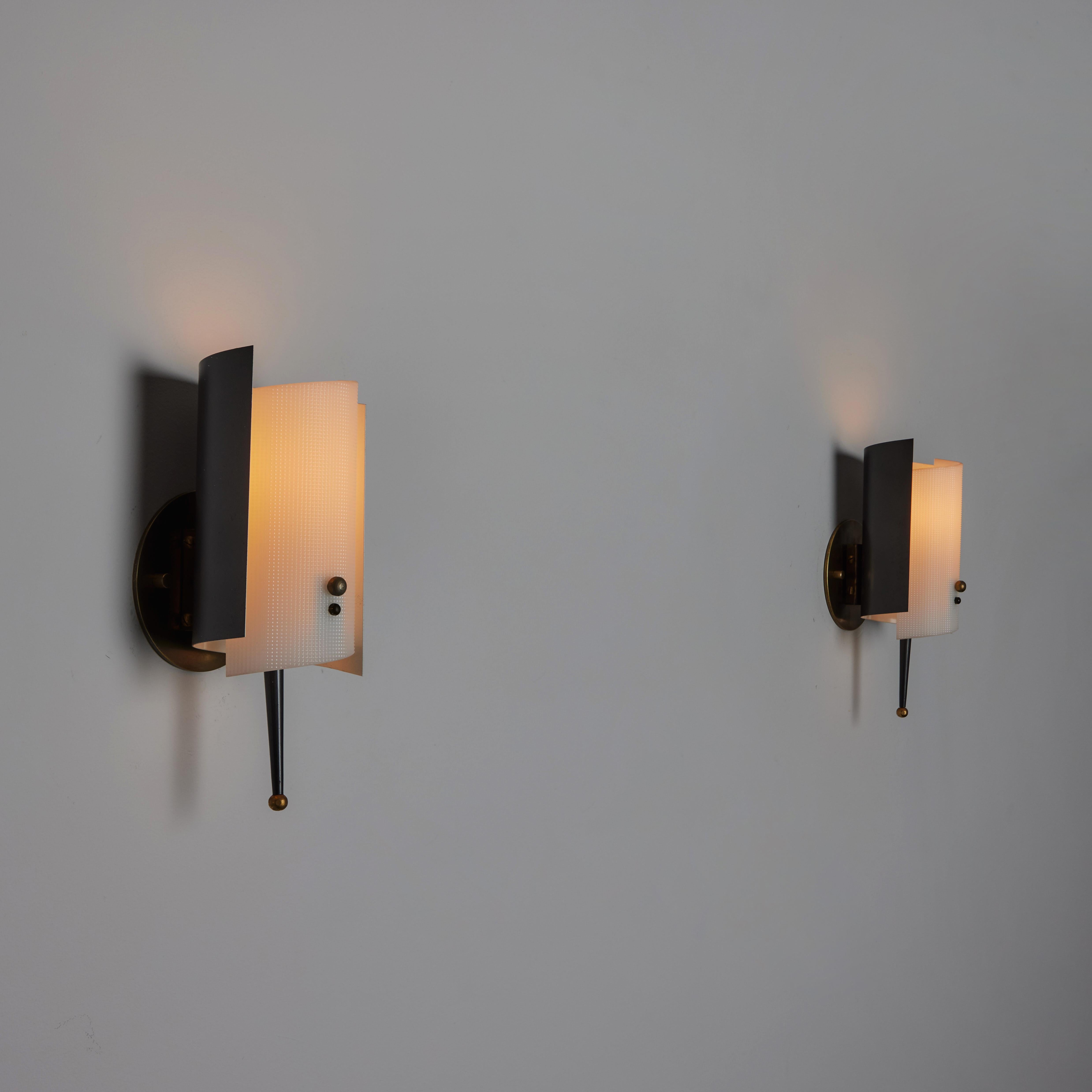 Pair of Sconces by Jacques Biny made in France, c.1950s. Featuring a curved metal enameled back with a white textured plexiglass diffuser, decorative spikes and brass details. Holds one E14 socket type per unit. We recommend one 25-40w bulb. Bulbs