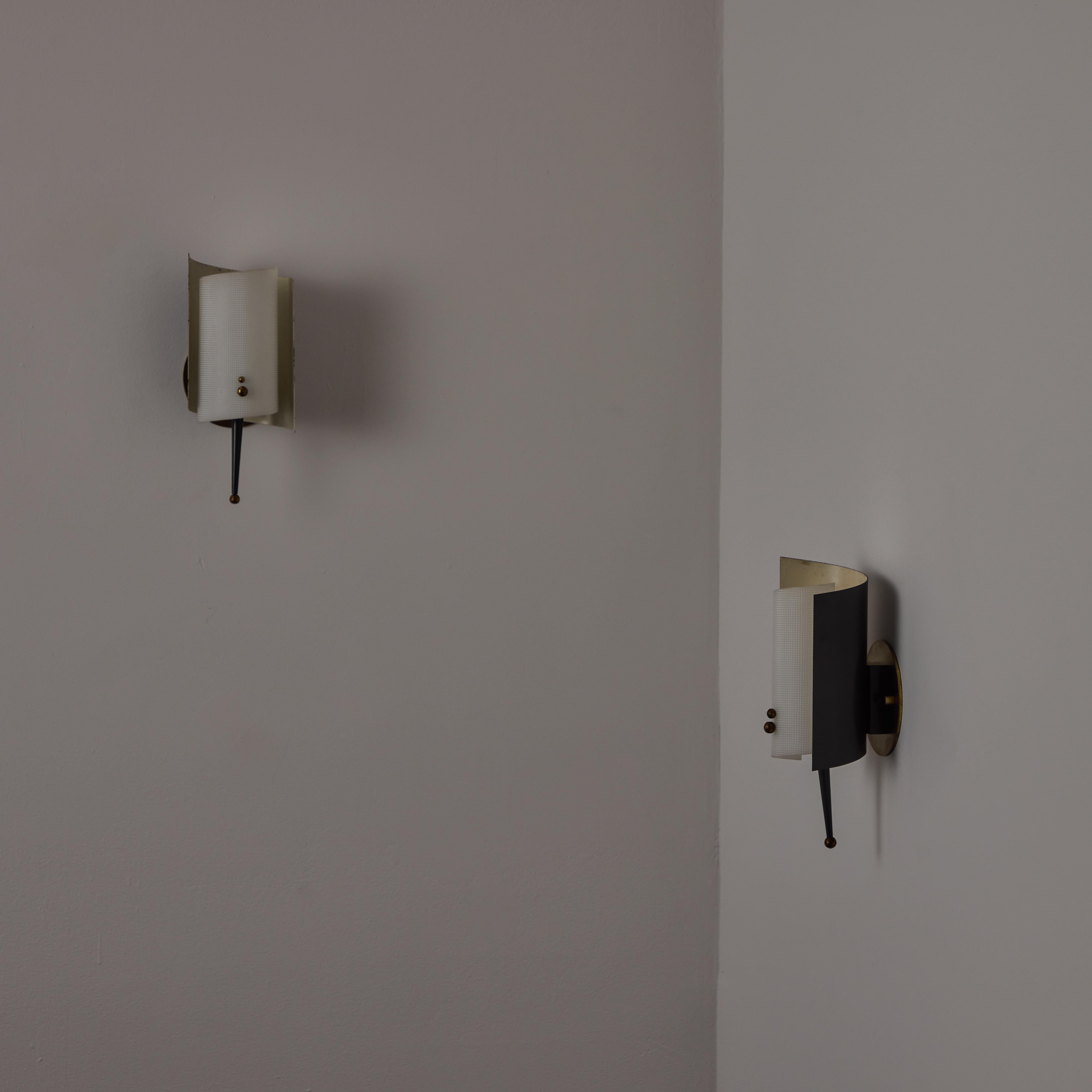 Pair of Sconces by Jacques Biny made in France, c.1950s. Featuring a curved metal enameled back with a white textured plexiglass diffuser, decorative spikes and brass details. Holds one E14 socket type per unit. We recommend one 25-40w bulb. Bulbs