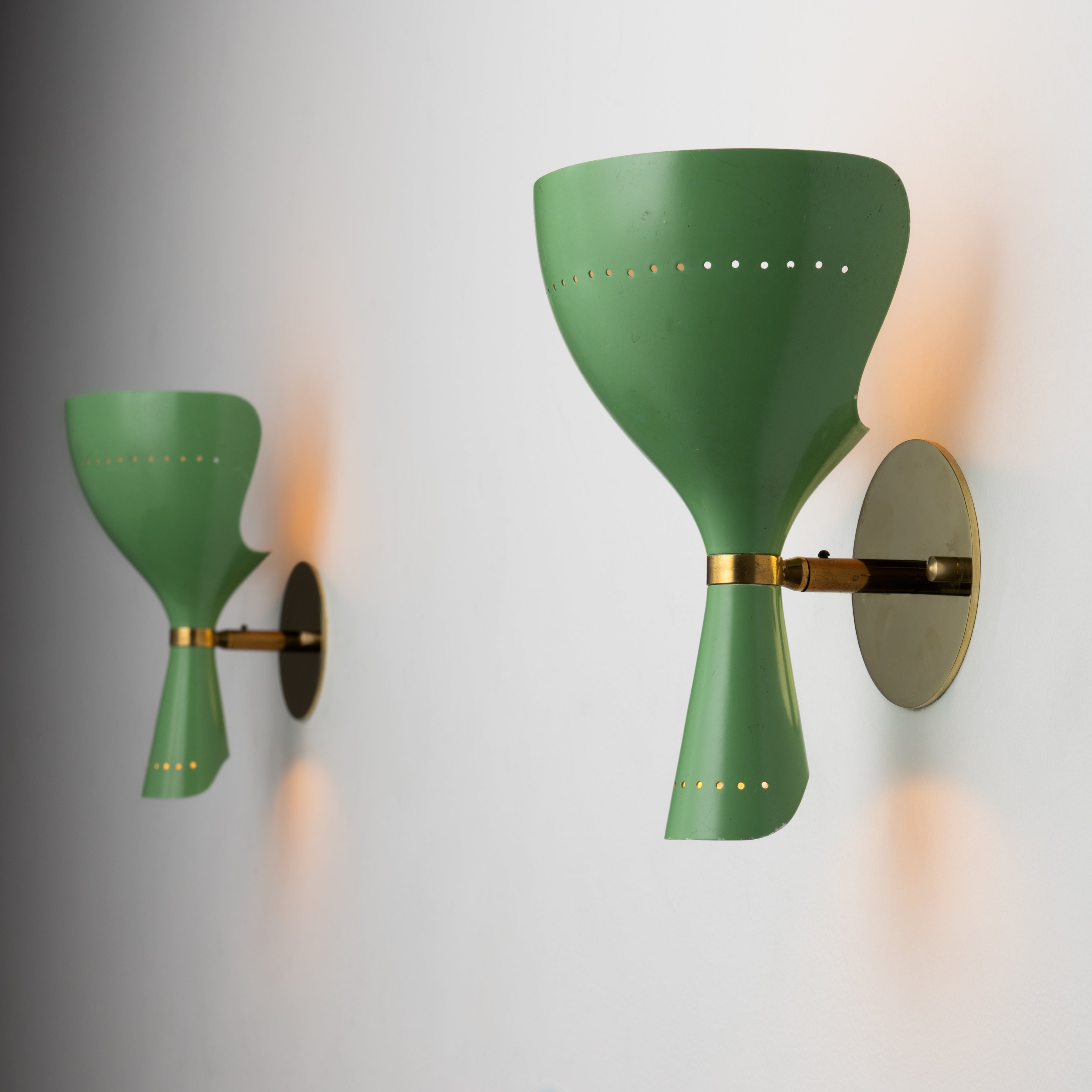 Pair of Sconces by Lumen. Designed and manufactured in Italy, circa the 1950s. These lamps feature a double headed conic design that provides a soft vertical illumination via two separate bulbs. Holds one E14 socket type, adapted for the US. We