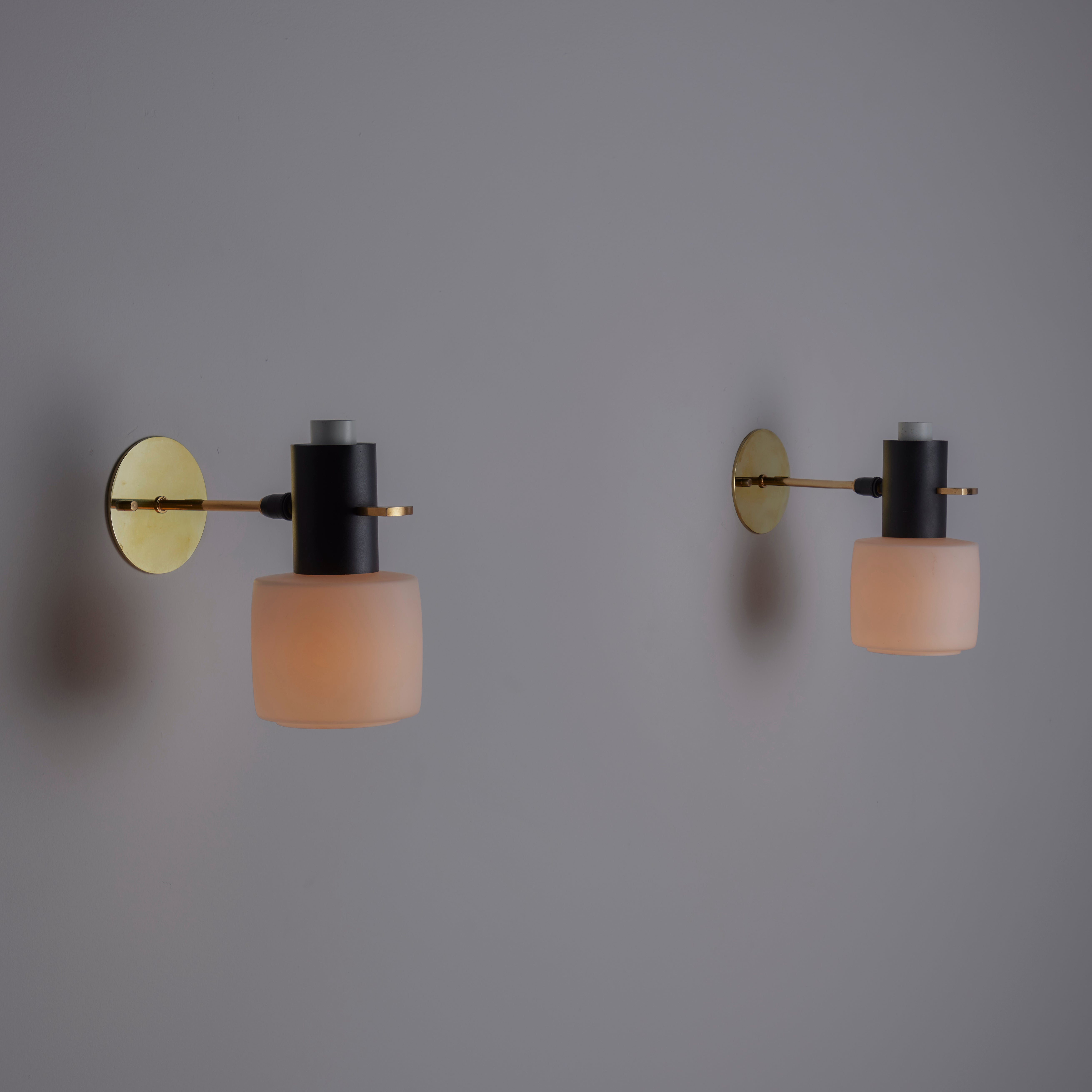 Pair of Sconces by Lunel. Designed and manufactured in Italy, circa the 1950s. Chalice-shaped opal glass cups nestle below a black enameled and brass armature construction. Each sconce holds a single E14 socket type, adapted for the US. We recommend
