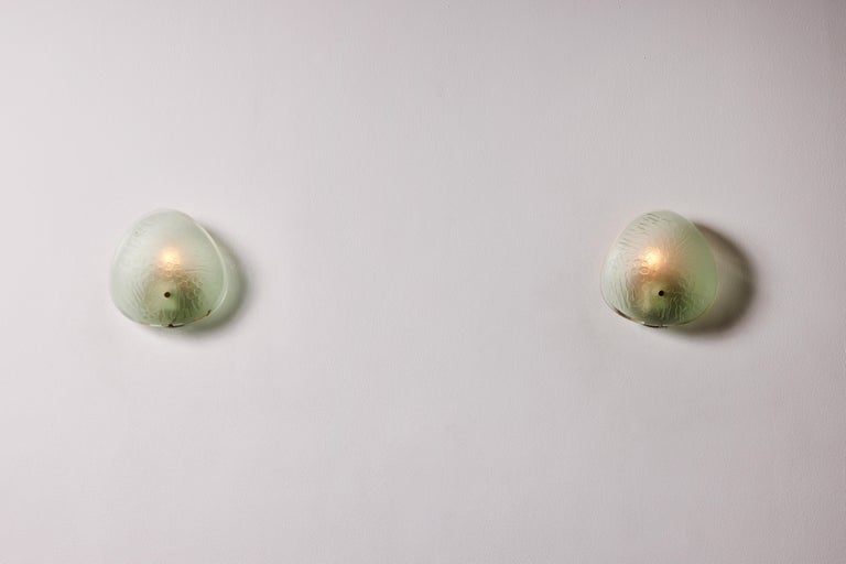 Pair of sconces by Max Ingrand for Fontana Arte. Variation of  Model 2199, designed and manufactured in Italy, 1955. Textured glass, brass. Custom brass backplates. We recommend one E12 60w maximum candelabra per light. Bulbs provided as a one time