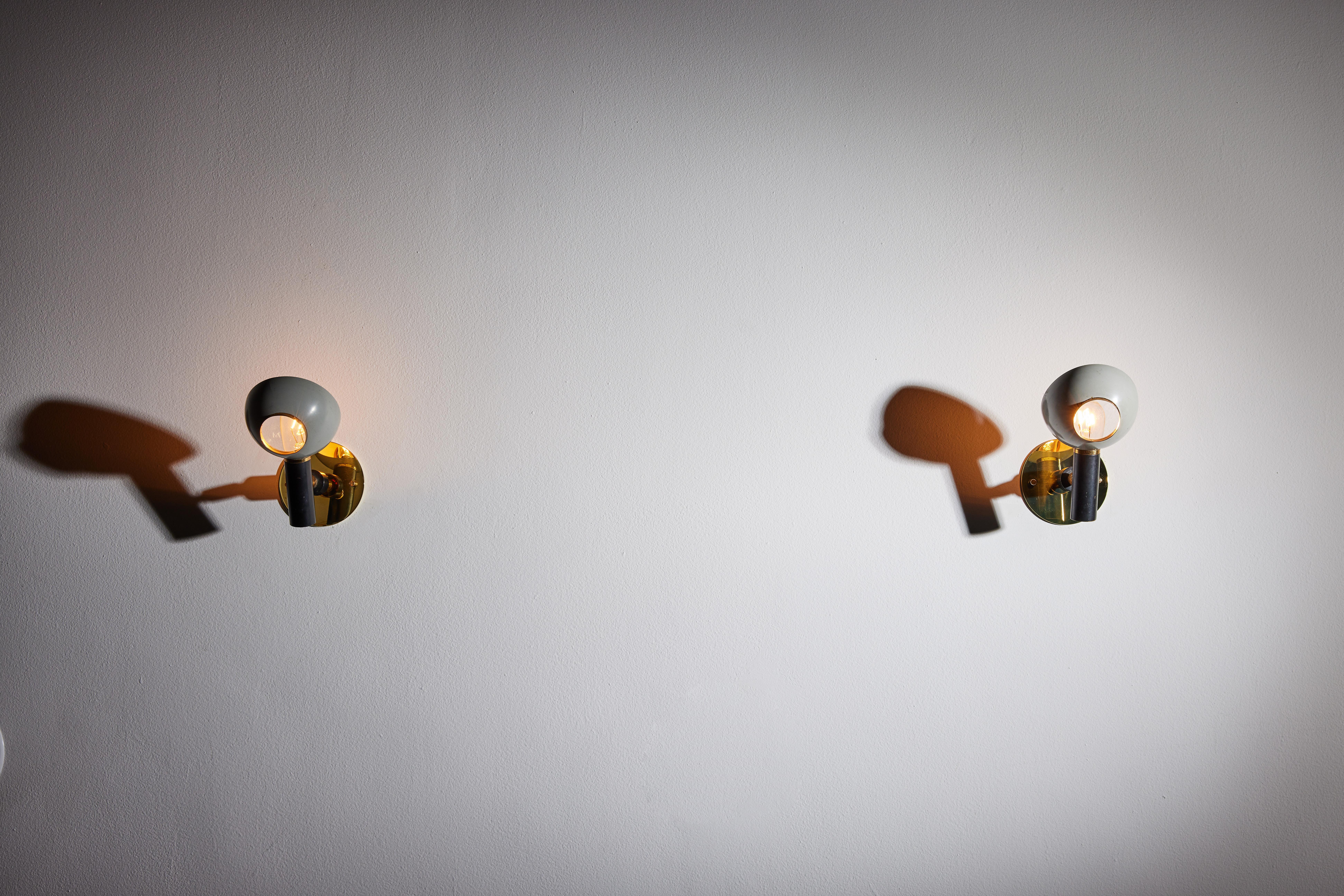 Pair of sconces by Oscar Torlasco for Lumi. Designed and manufactured in Italy, circa 1950s. Painted aluminum, metal and brass. Rewired for U.S. standards. Shades adjust to various positions. We recommend one E14 candelabra 40w maximum bulb per
