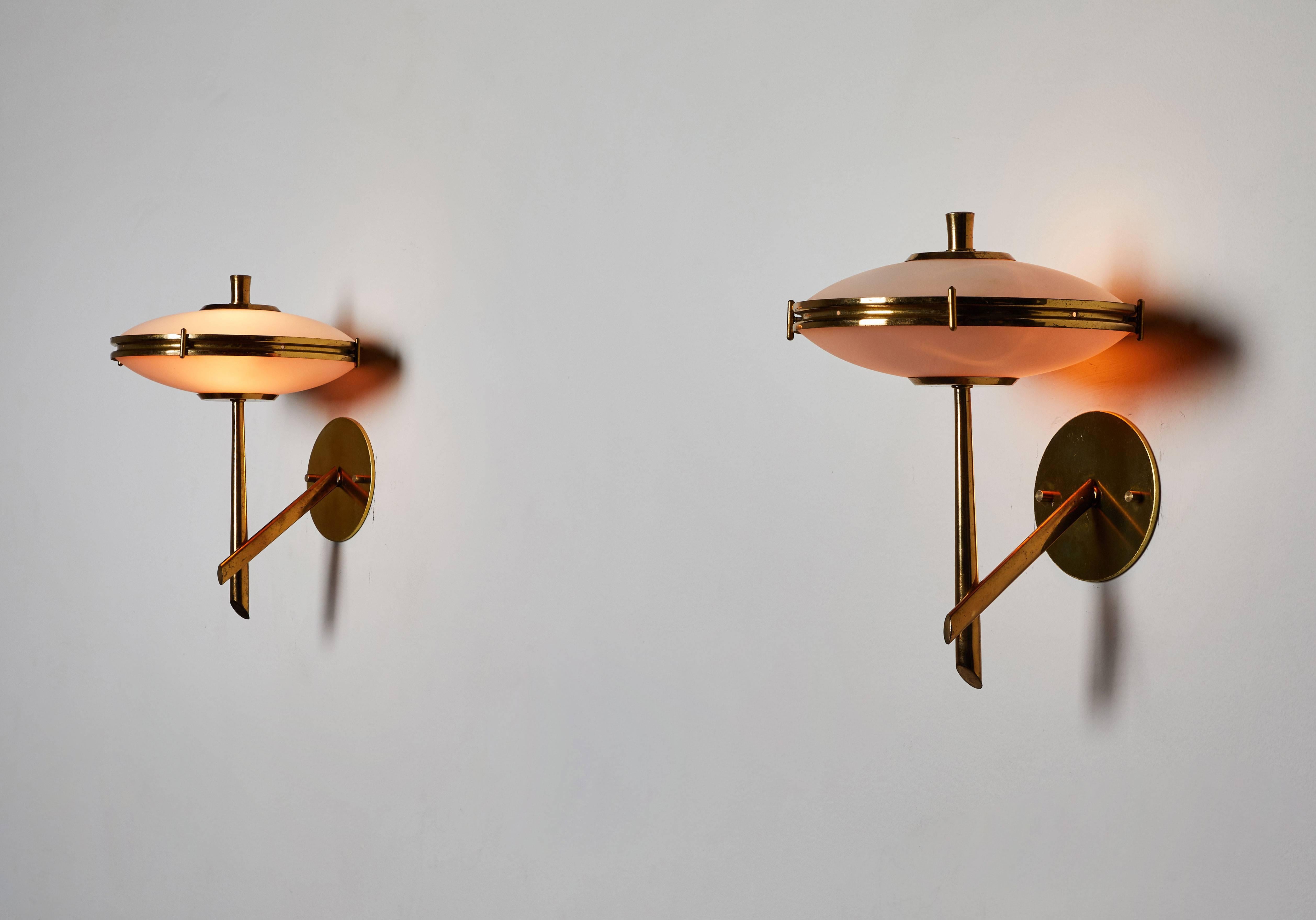 Pair of sconces by Stilnovo. Designed and manufactured in Italy, circa 1950s. Brass, enameled metal and brushed satin glass diffusers. Wired for US junction boxes. Custom brass backplates. Retains the original manufacturer's stamp. Each light takes