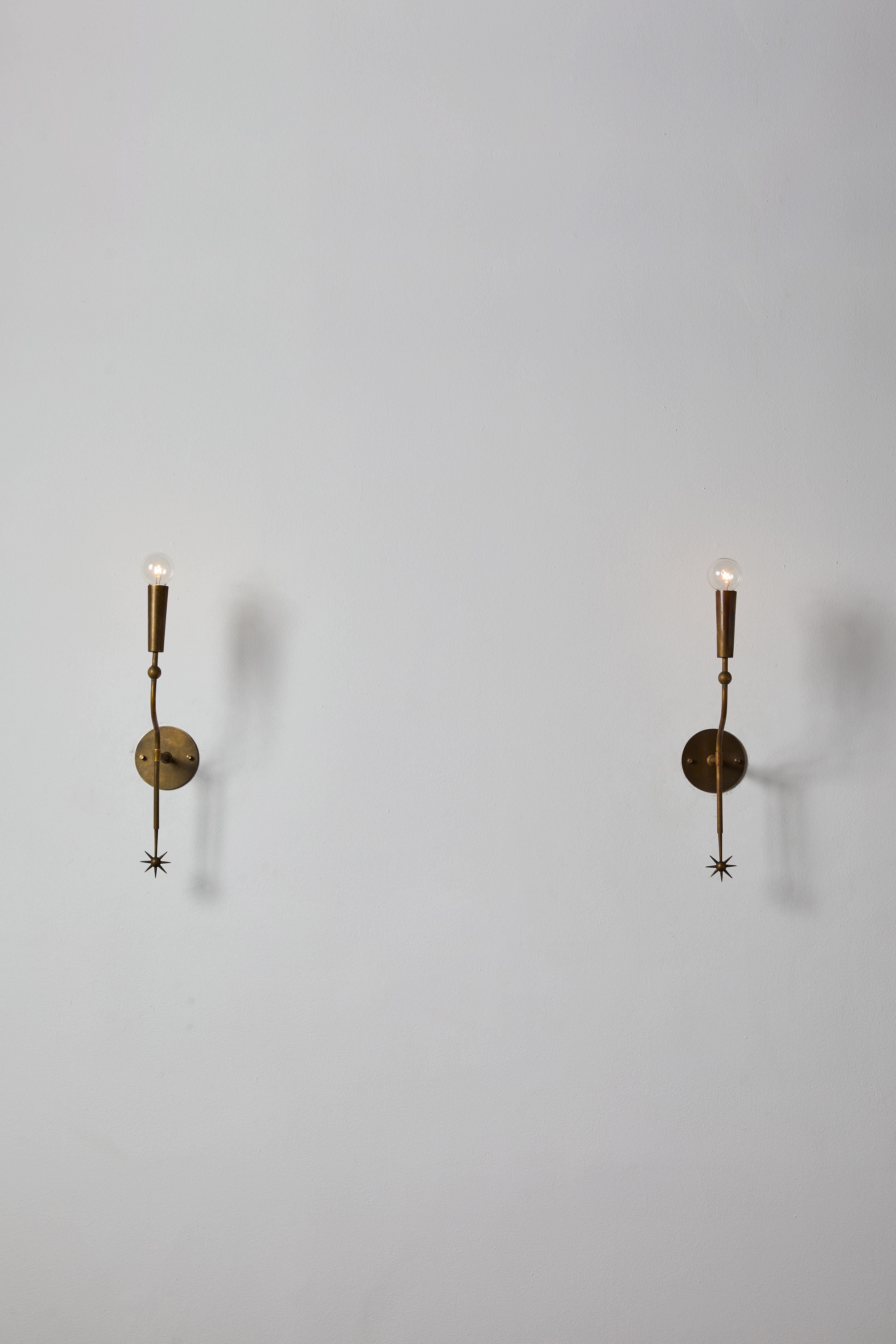 Pair of sconces by Stilnovo. Manufactured in Italy, circa 1950s. Brass, custom brass backplate. Rewired for U.S. standards. We recommend one E14 European 60w maximum candelabra bulb per sconce. Bulbs provided as a one time courtesy.