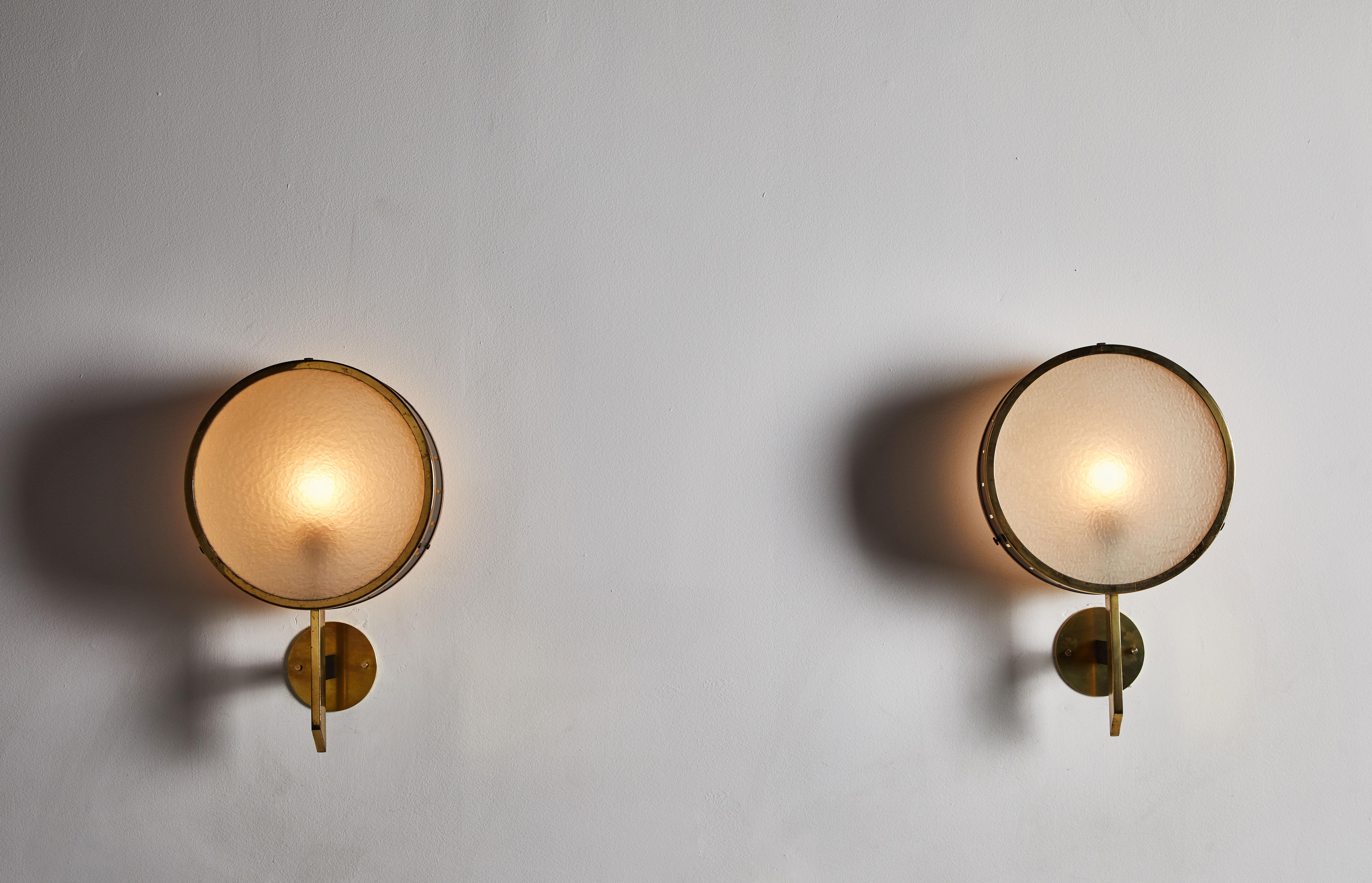 Pair of sconces manufactured by Stilnovo in Italy, circa 1950s. Textured glass diffuser, perforated enameled metal shade with brass hardware. Rewired for US junction boxes. Each light takes one E26 60w maximum bulbs.