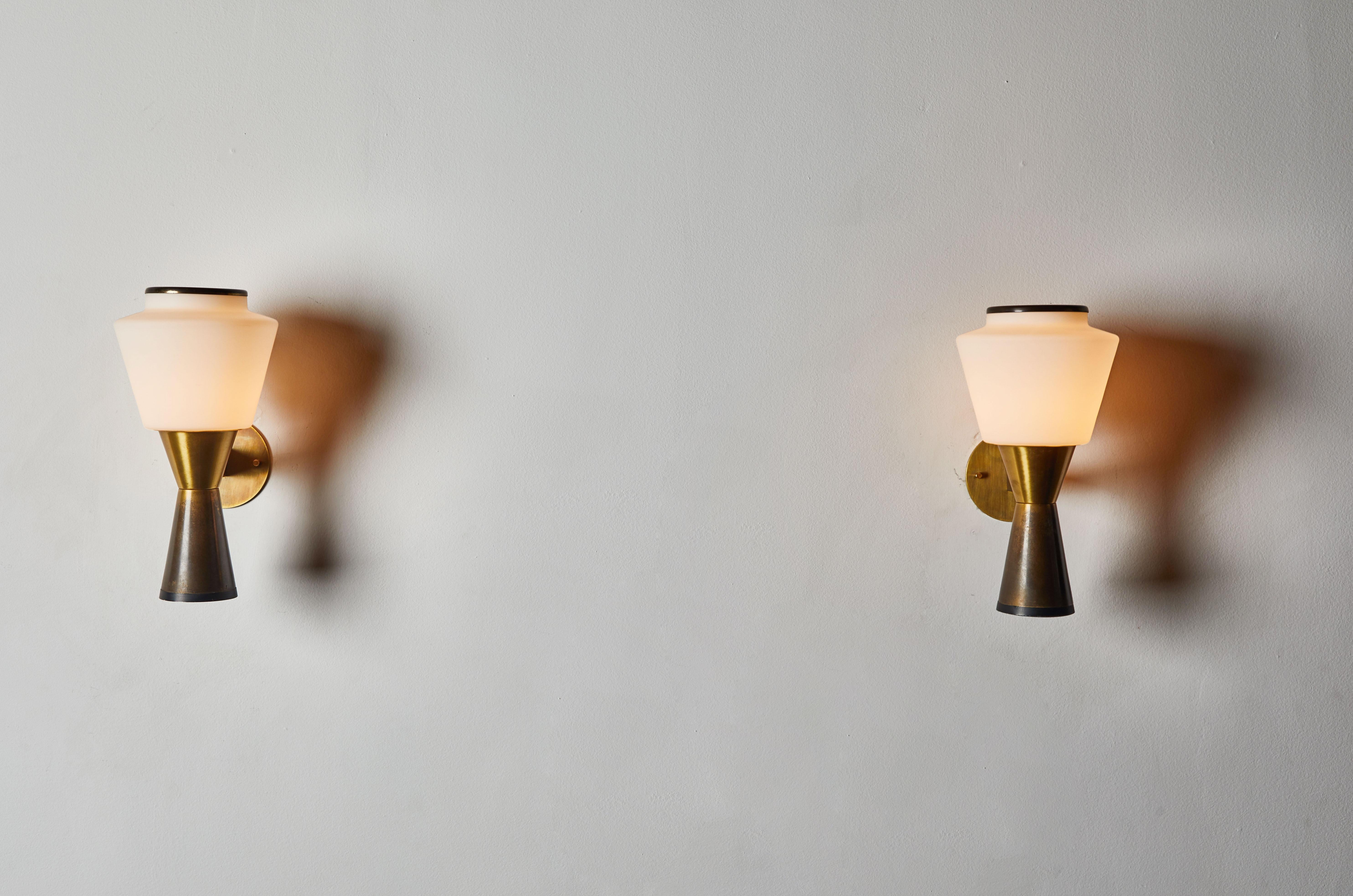 Pair of sconces by Stilnovo. Manufactured in Italy, circa 1960s. Patinated brass with brushed satin glass diffusers. Custom brass backplate. Rewired for US junction boxes. Each light takes one E27 60w maximum bulb.