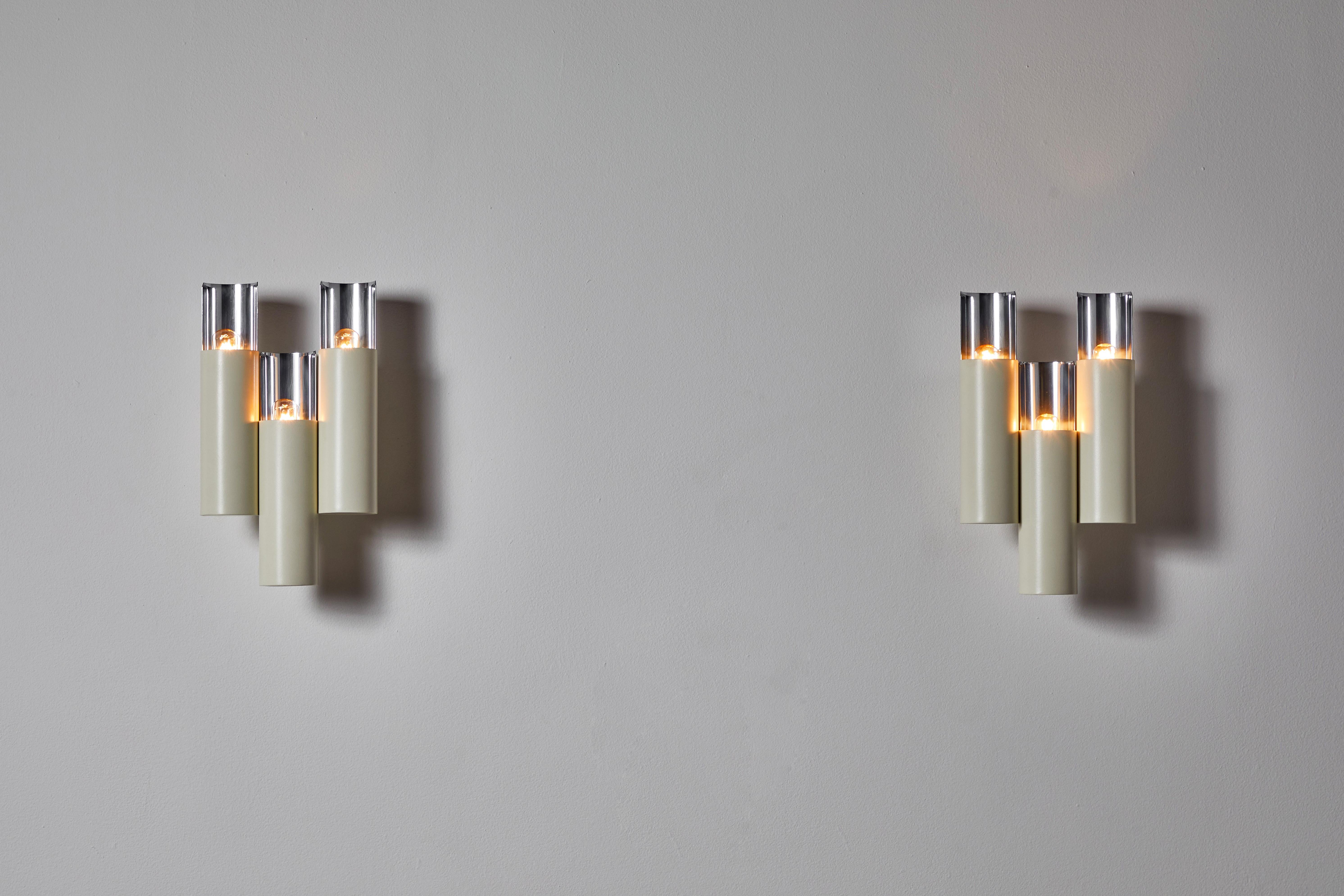Pair of sconces by Stilnovo. Manufactured in Italy, circa 1960s. Enameled aluminum, plated chrome. Wired for U.S. standards. We recommend three European 20w maximum bulbs per light. Bulbs provided as a one time courtesy.