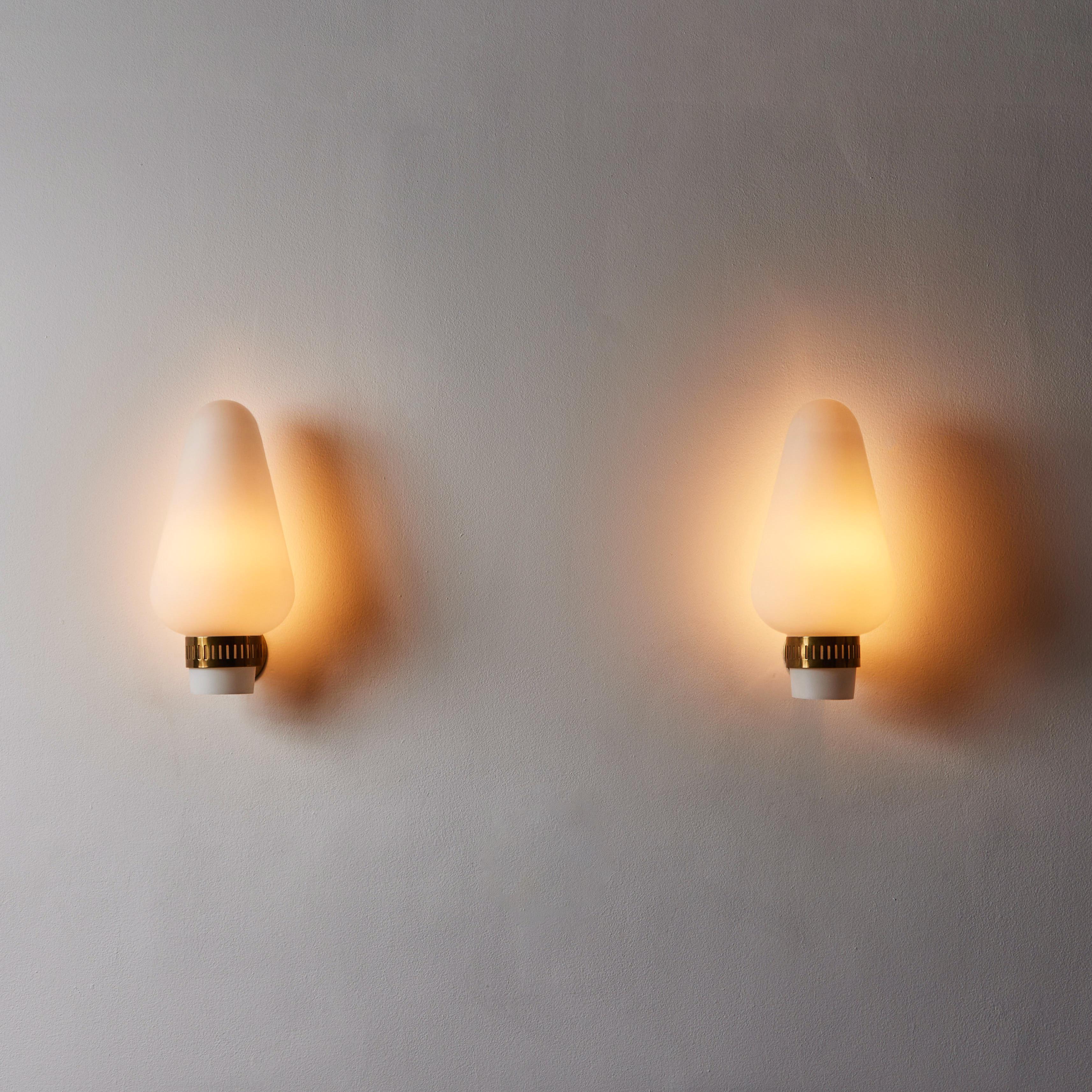 Pair of sconces by Stilnovo. Manufactured in Italy, circa 1960s. Brushed satin glass, brass. Custom brass backplate. Wired for U.S. standards. We recommend one E26 60w maximum bulb per sconce. Bulbs provided as a onetime courtesy.