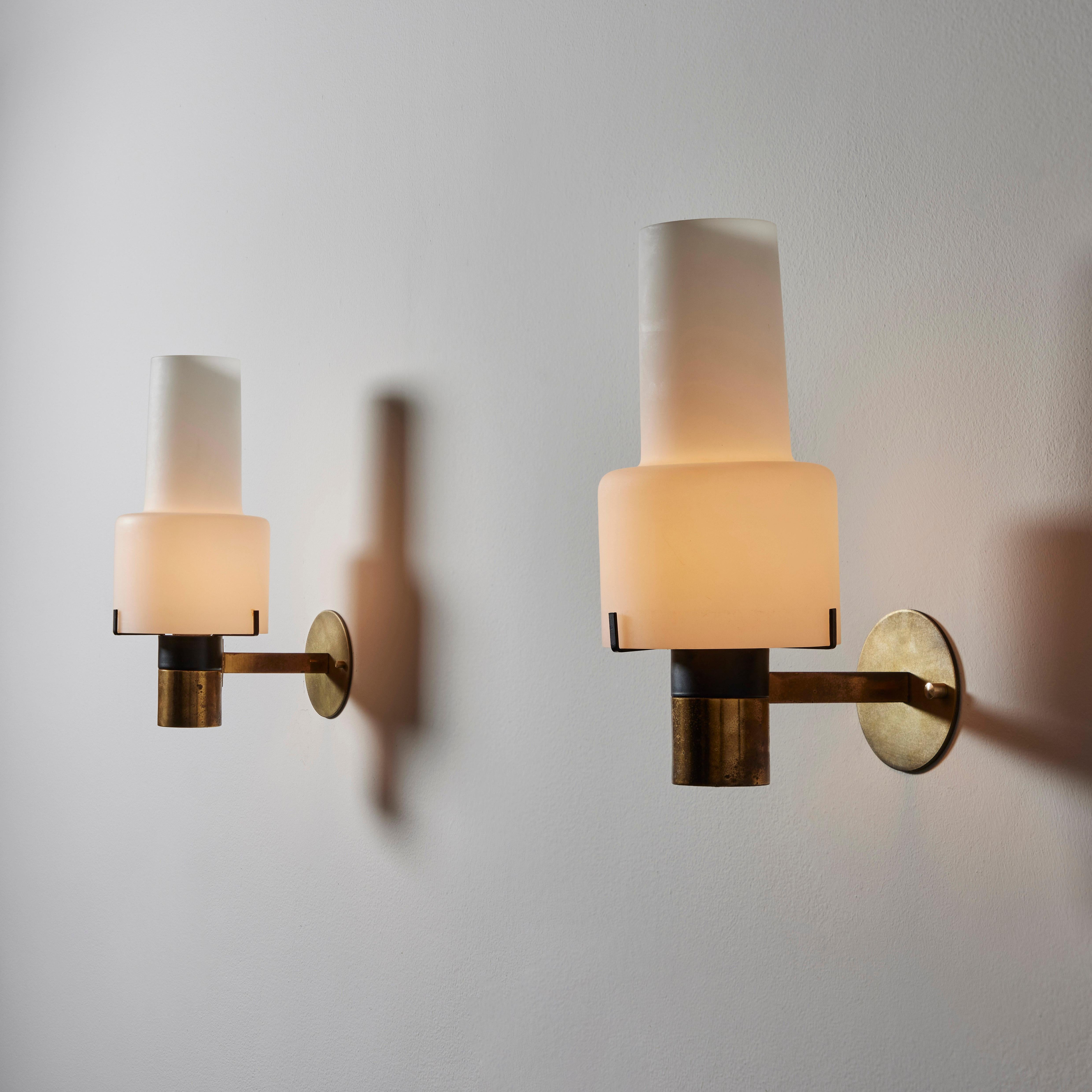 Pair of sconces by Stilnovo. Manufactured in Italy, circa 1950's. Brushed satin glass diffuser. Custom brass backplates. We recommend on E27 100w maximum bulb per fixture. Bulbs not included. Retains manufacturer's original label.