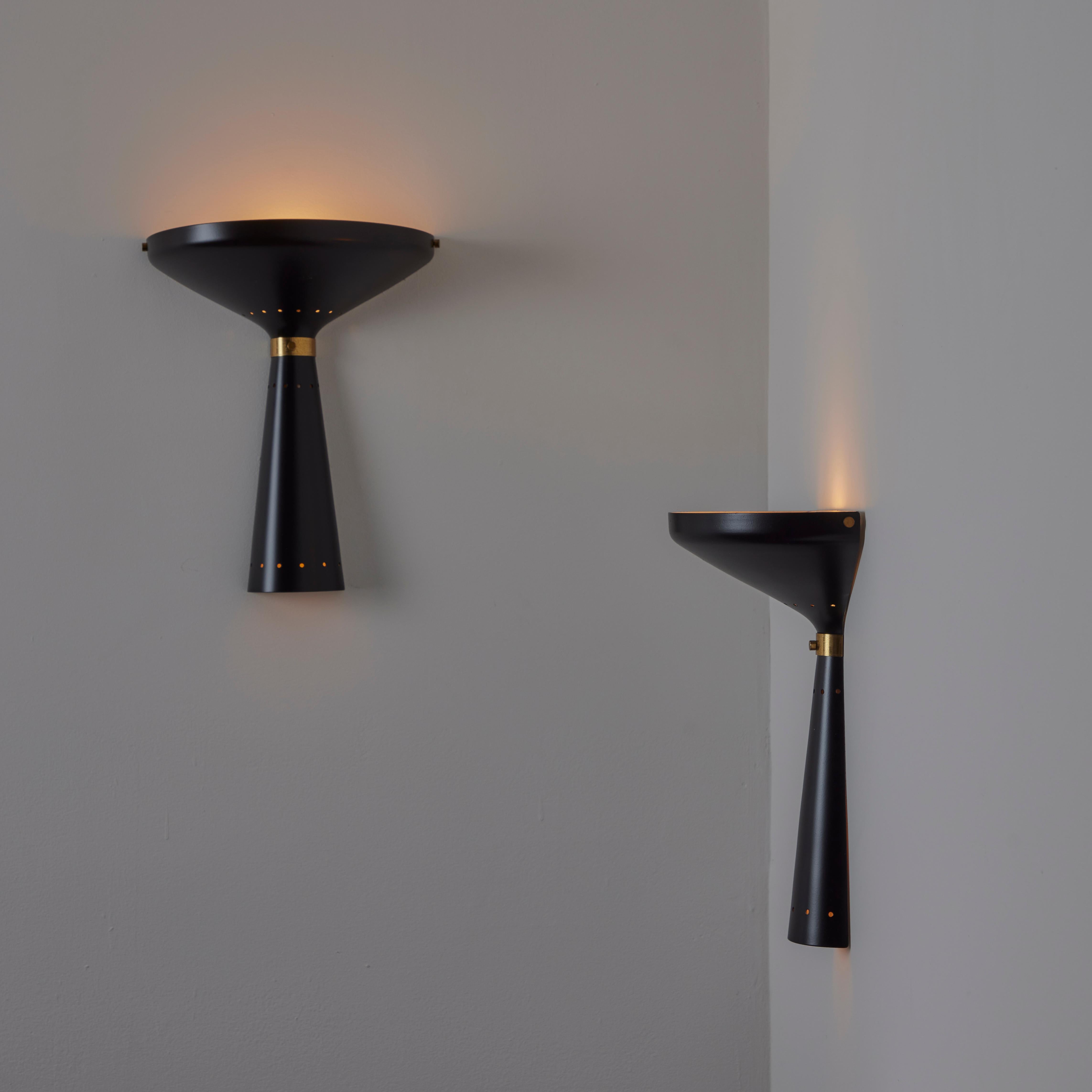 Ein Paar Stilnovo-Leuchter. Entworfen in Italien, etwa in den 1960er Jahren. Schwarz emaillierte Wandlampen mit Fliege und Messingkragen. Die Perforation auf der oberen Hälfte sorgt für ein schönes Detail. Für eine einzelne E27-Fassung, angepasst an
