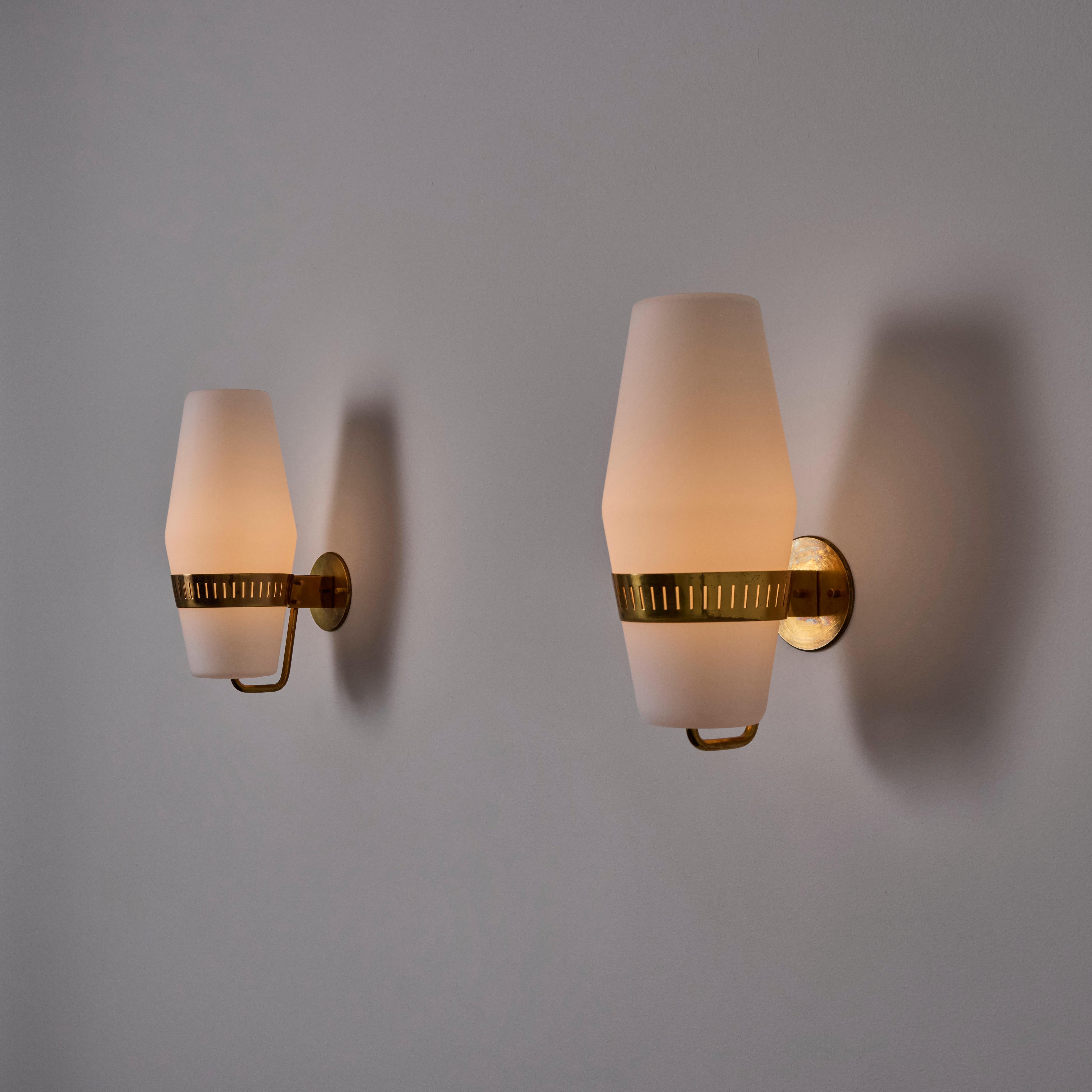 Pair of Sconces by Stilnovo (Italy, c. 1960s)

Opaline glass nestled into a slitted brass holder. Brass details are polished and aged. Each sconce holds a single e27 socket-type, adapted for the US. We recommend a 40w max bulb or LED equivalent.