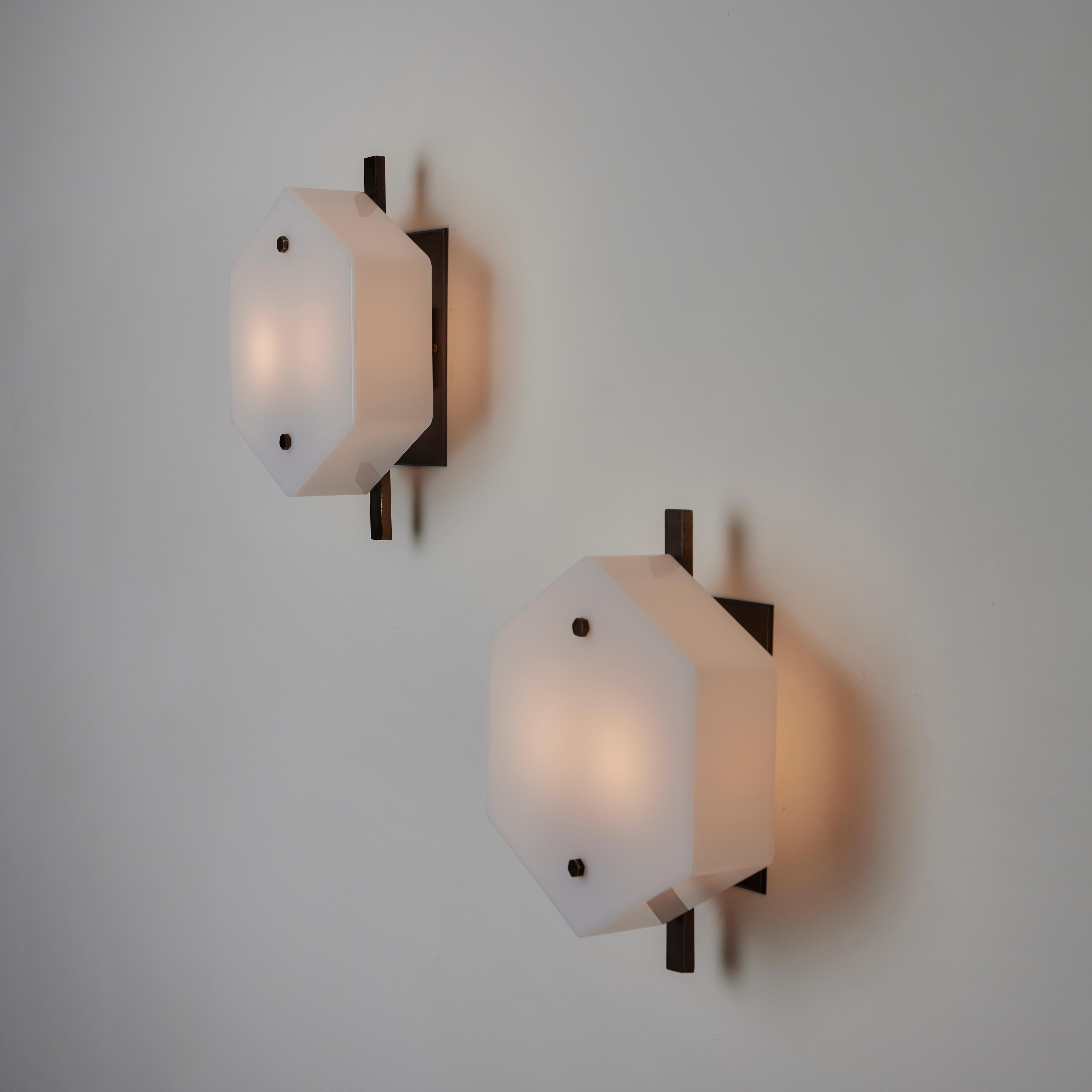 Pair of Sconces by Stilux. Designed and manufactured in Italy, circa the 1960s. Hexagonal acrylic diffusers alongside a dark patinated brass stem. Each lamp holds a dual E14 socket type, adapted for the US. We recommend a 25w max bulb or LED for
