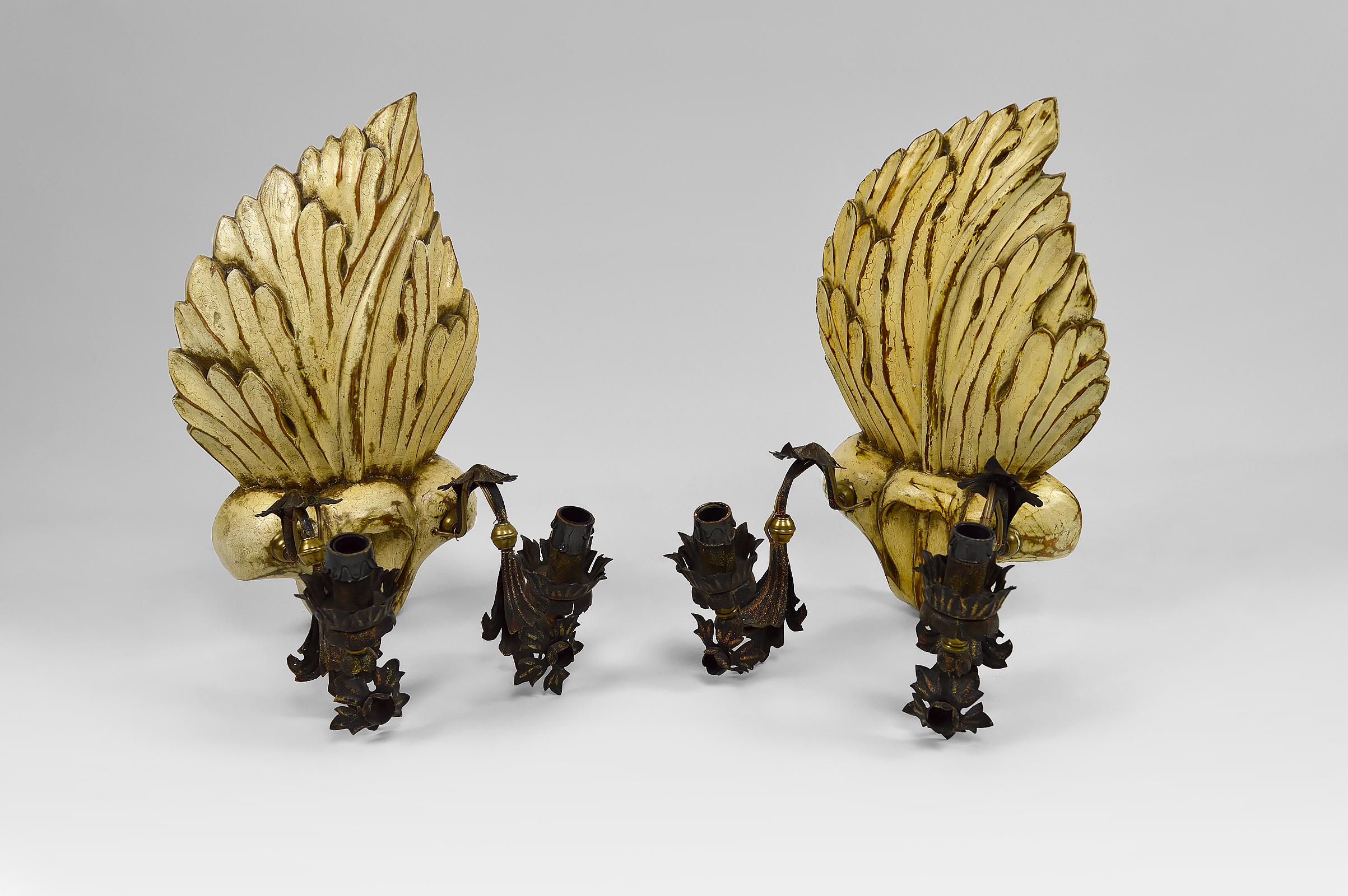 Pair of carved, painted and patinated wooden sconces.

Each wall lamp has 2 wrought iron arms supporting a fire.

Hollywood Regency / Baroque Revival, France or Italy. Circa 1950-1960
In the style of the productions of Ramsay, Jansen, Moreux.

In