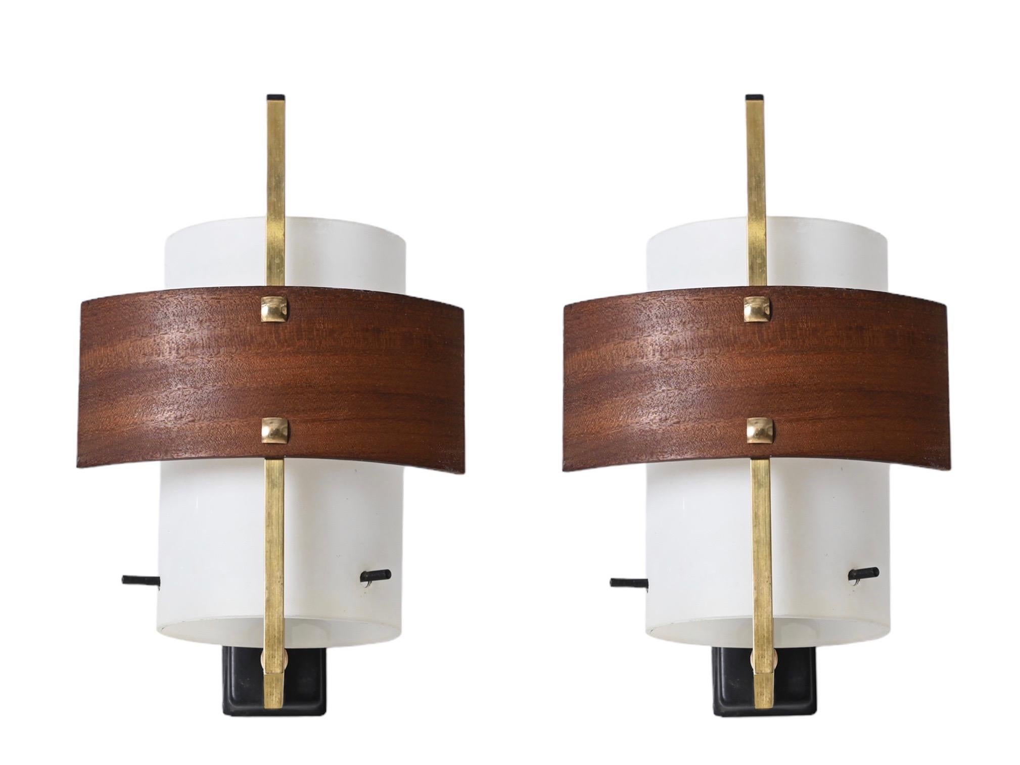 Gorgeous pair of sconces in opaline glass, brass and teak wood. This charming wall lights were designed by Studio Reggiani in Italy in the 1960s. 

These sconces feature a brass arm with three black lacquered metal supports that hold a stunning