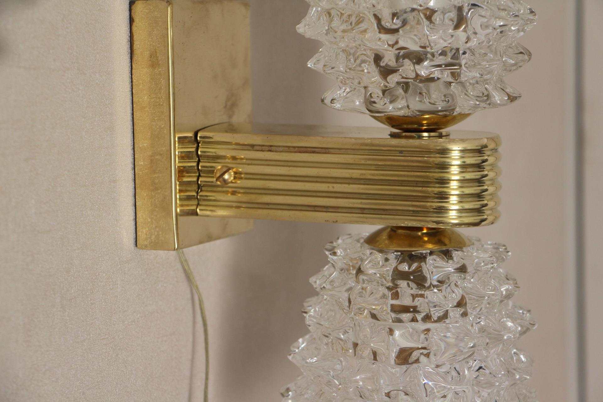 This magnificent pair of sconces from Murano was made according to the hand made rostrato technique; It means that each spike of glass was individually pulled in relief.
Moreover these sconces feature 2 glass shades each and give pleasant and warm