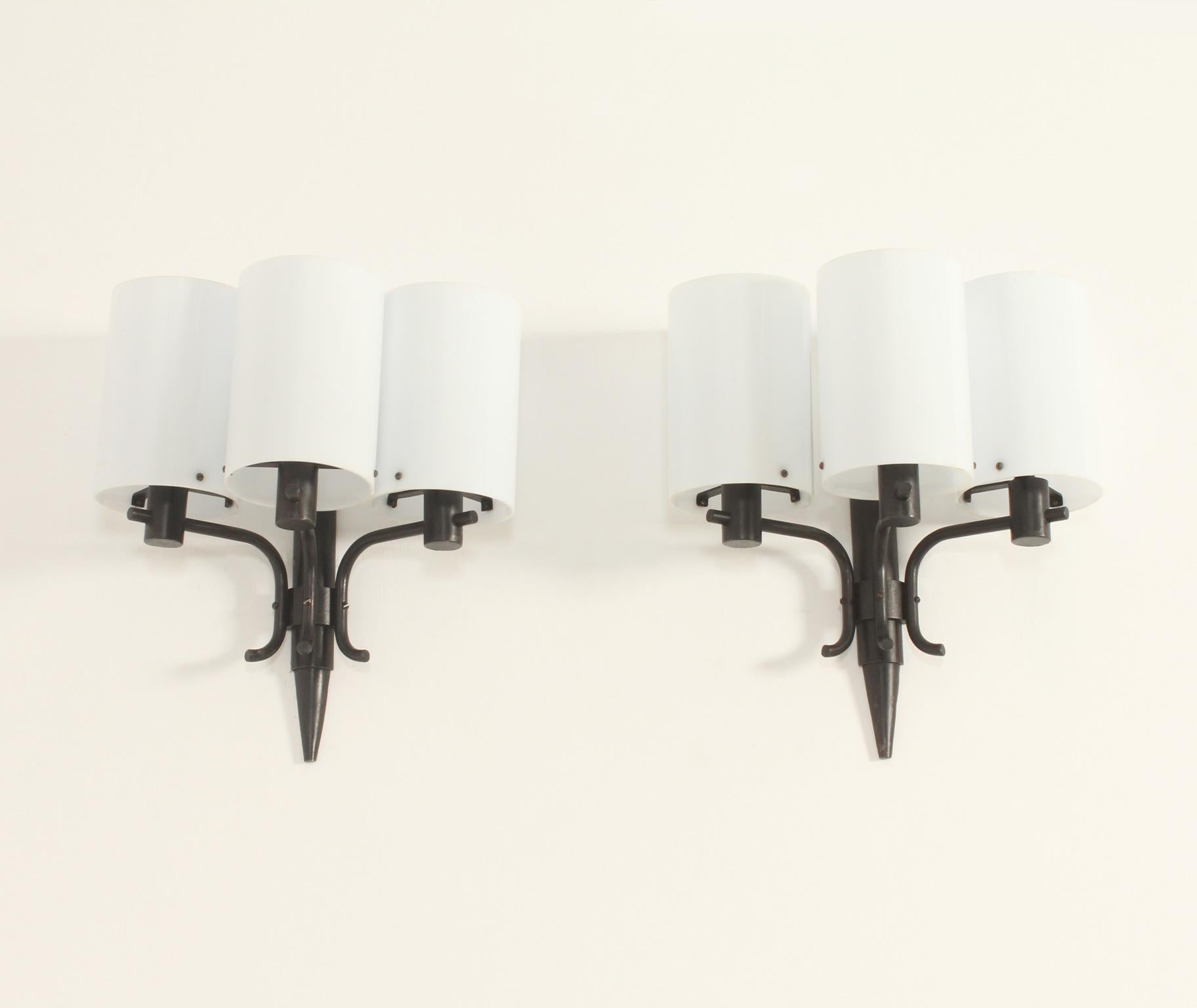 Pair of sconces designed in 1960's by Jordi Vilanova, Spain. Hand wrought iron patinated in black and three white methacrylate shades.