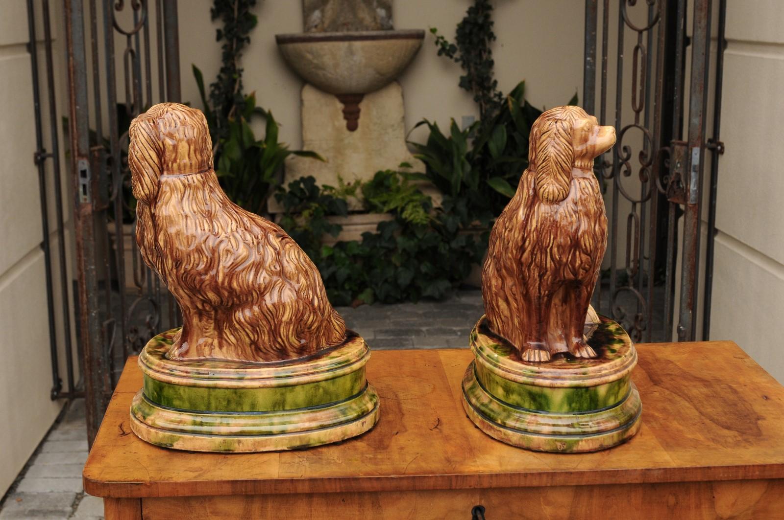 A pair of Scottish Victorian period glazed spaniel dogs potteries on oval bases from the late 19th century. Born in Scotland during the late Victorian era, this spectacular pair of dog sculptures each features a spaniel, obediently seated on an oval
