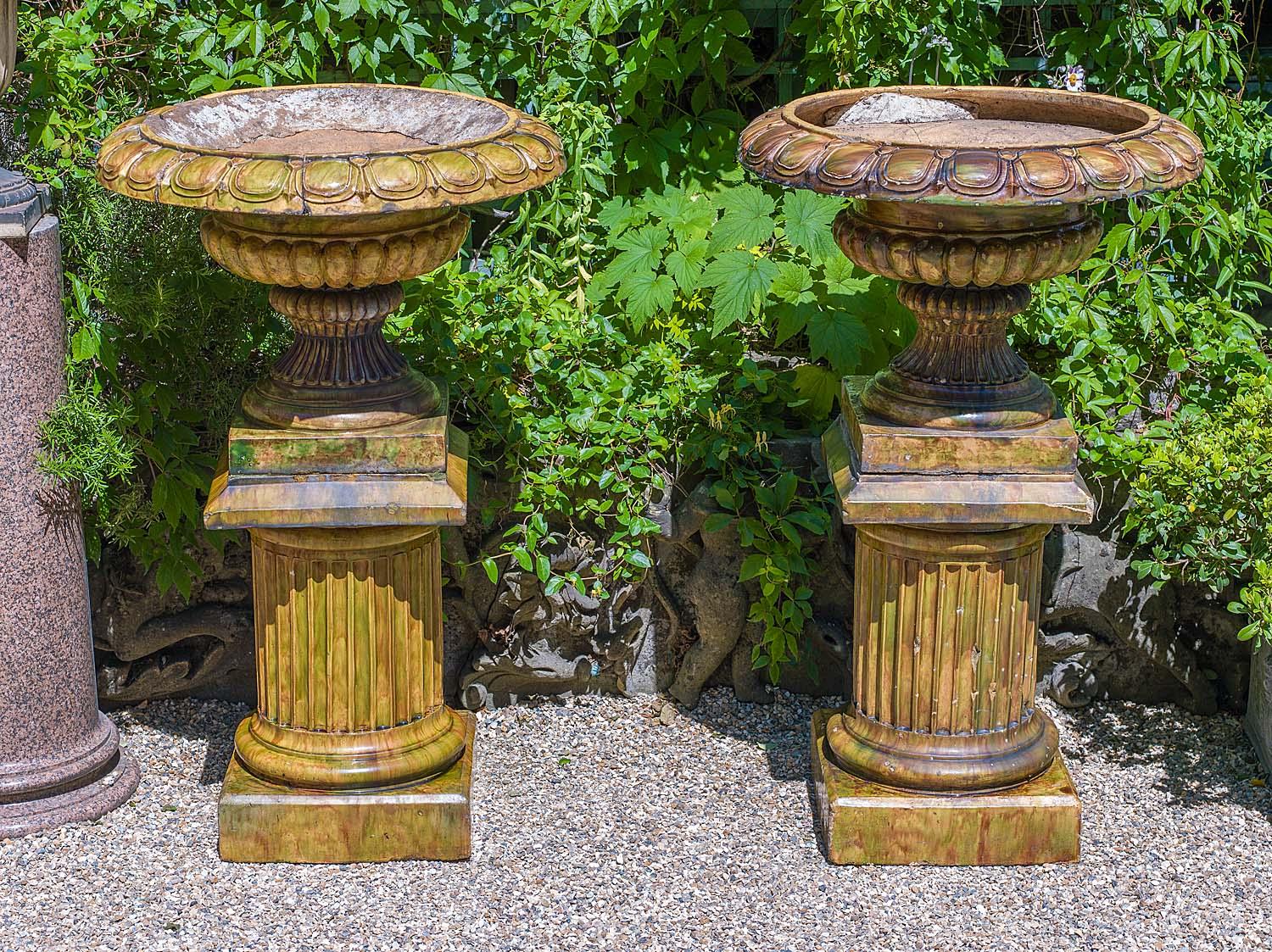 A large pair of Scottish glazed stoneware Campan style garden urns. The wide brimmed bowls with linked egg and tongue detail above gadrooned stems raised on stepped bases resting on sturdy reeded column stands.
Scottish late 19th-early 20th