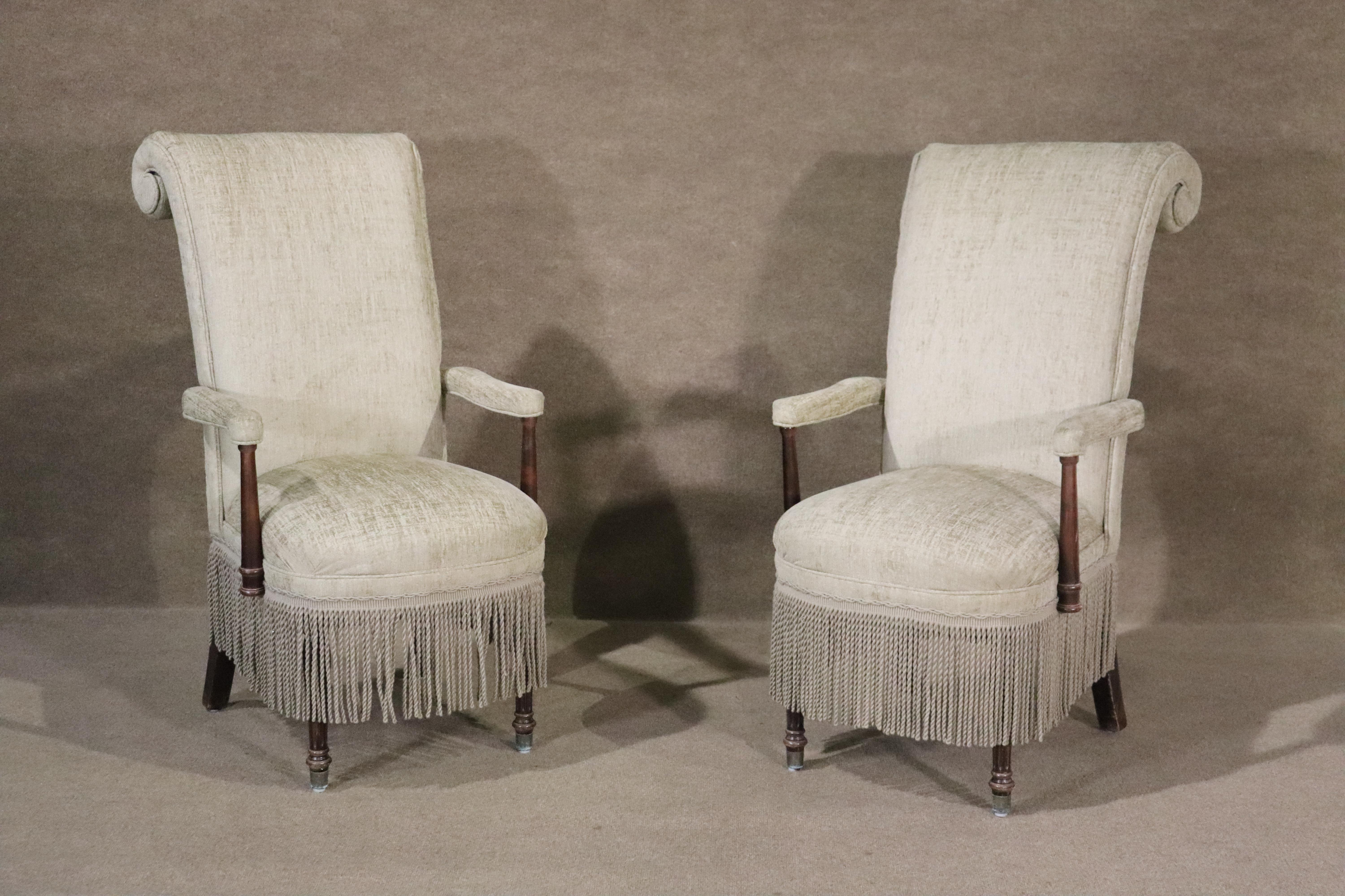 This set of upholstered mid-century armchairs are a gorgeous and tasteful addition to any home. Long tassels hang between the legs to add a natural touch to a distinct scroll-back design.

Please confirm location (NY or NJ)