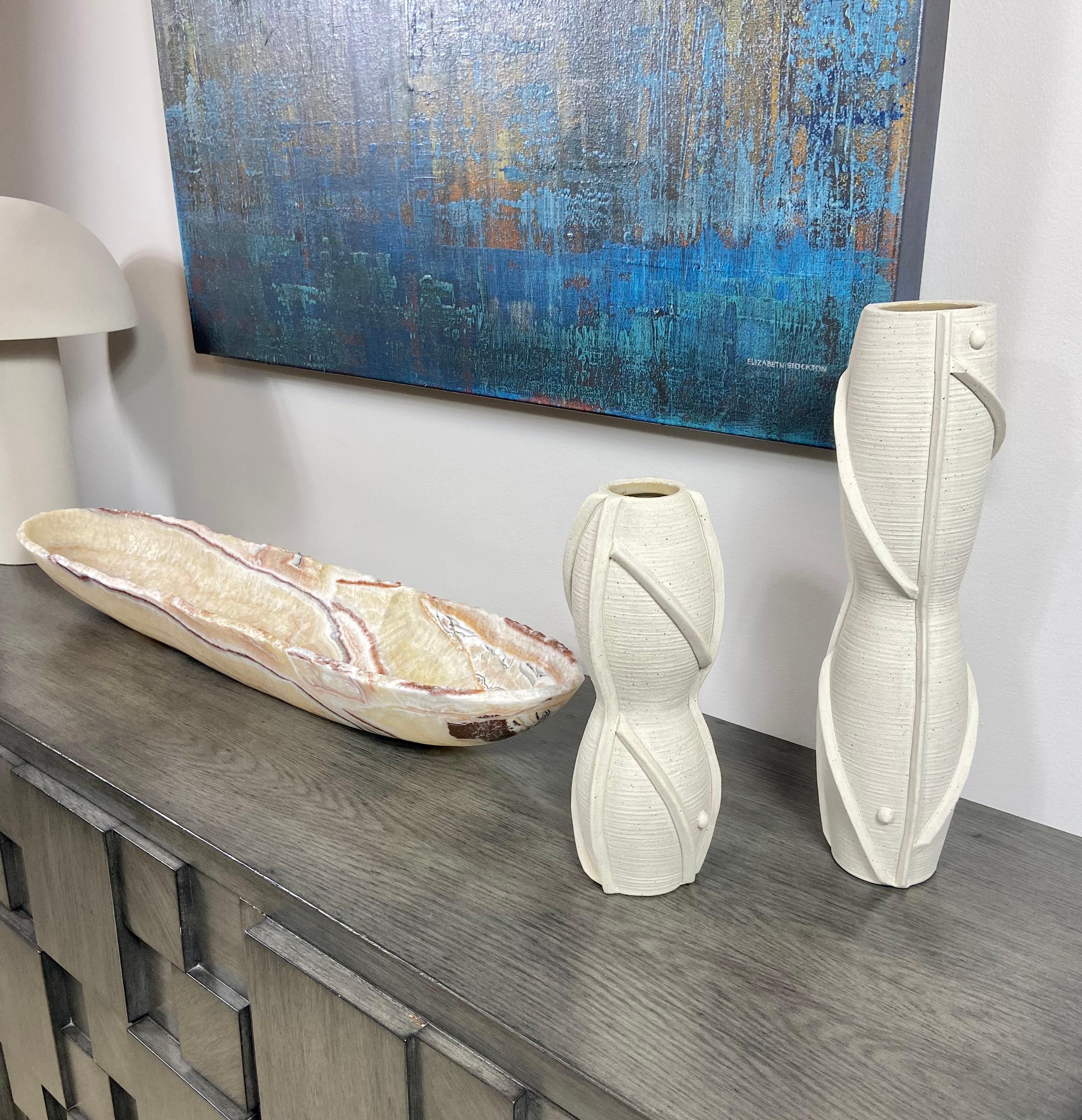 A pair of sinuous ceramic vases with a raw textured off-white glaze and hand-applied and raised detailing. These gorgeous statement vases are hand made by Los Angeles ceramist Titia Estes who is known for her sculptural work. Sold as a pair only.