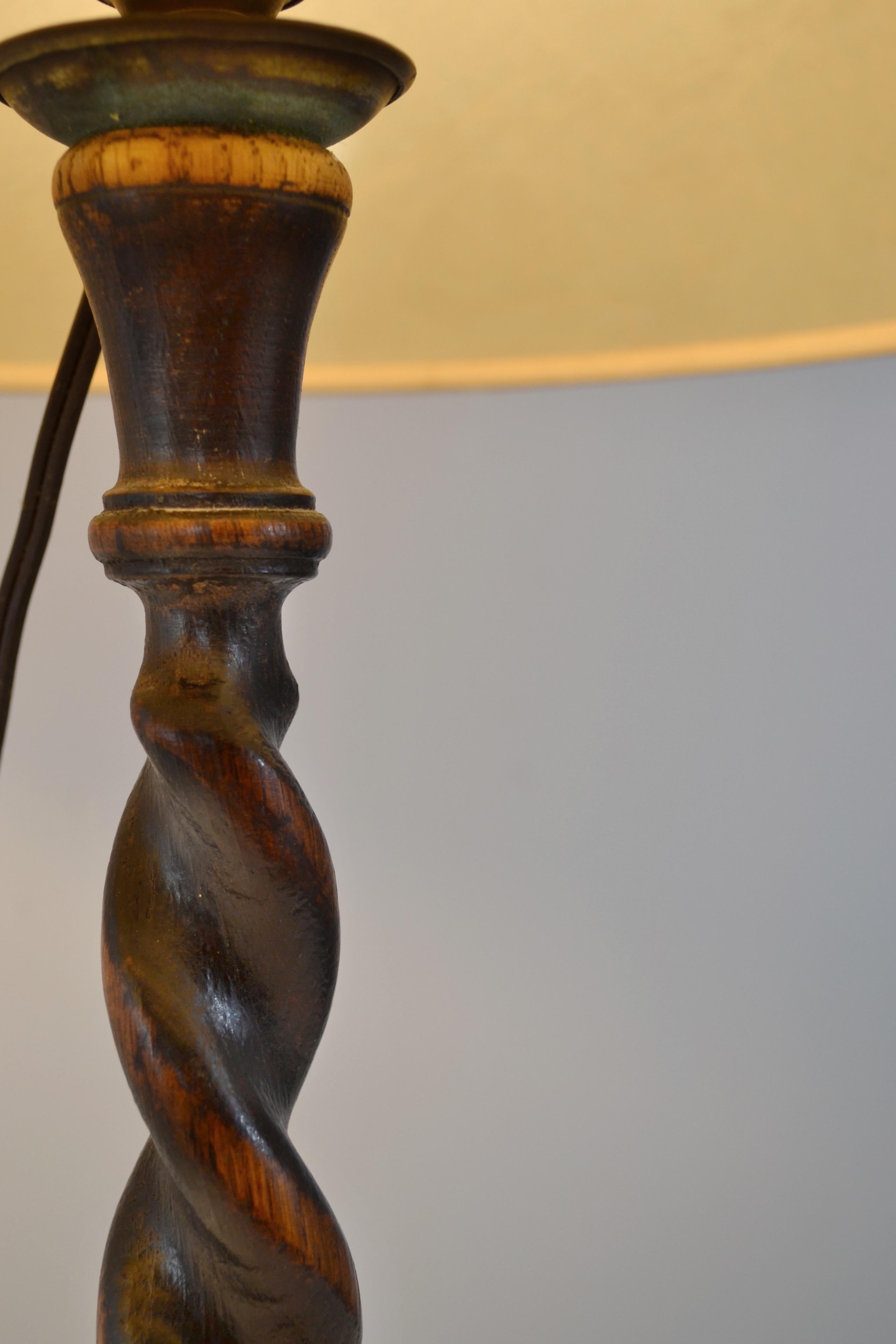 Coppia di lampade da tavolo in quercia scolpita, metà del XX secolo, con basi ritorte finemente intagliate in una profonda patina scura, completate da paralumi nello stile della tradizionale vescica di maiale che proiettano una luce calda e