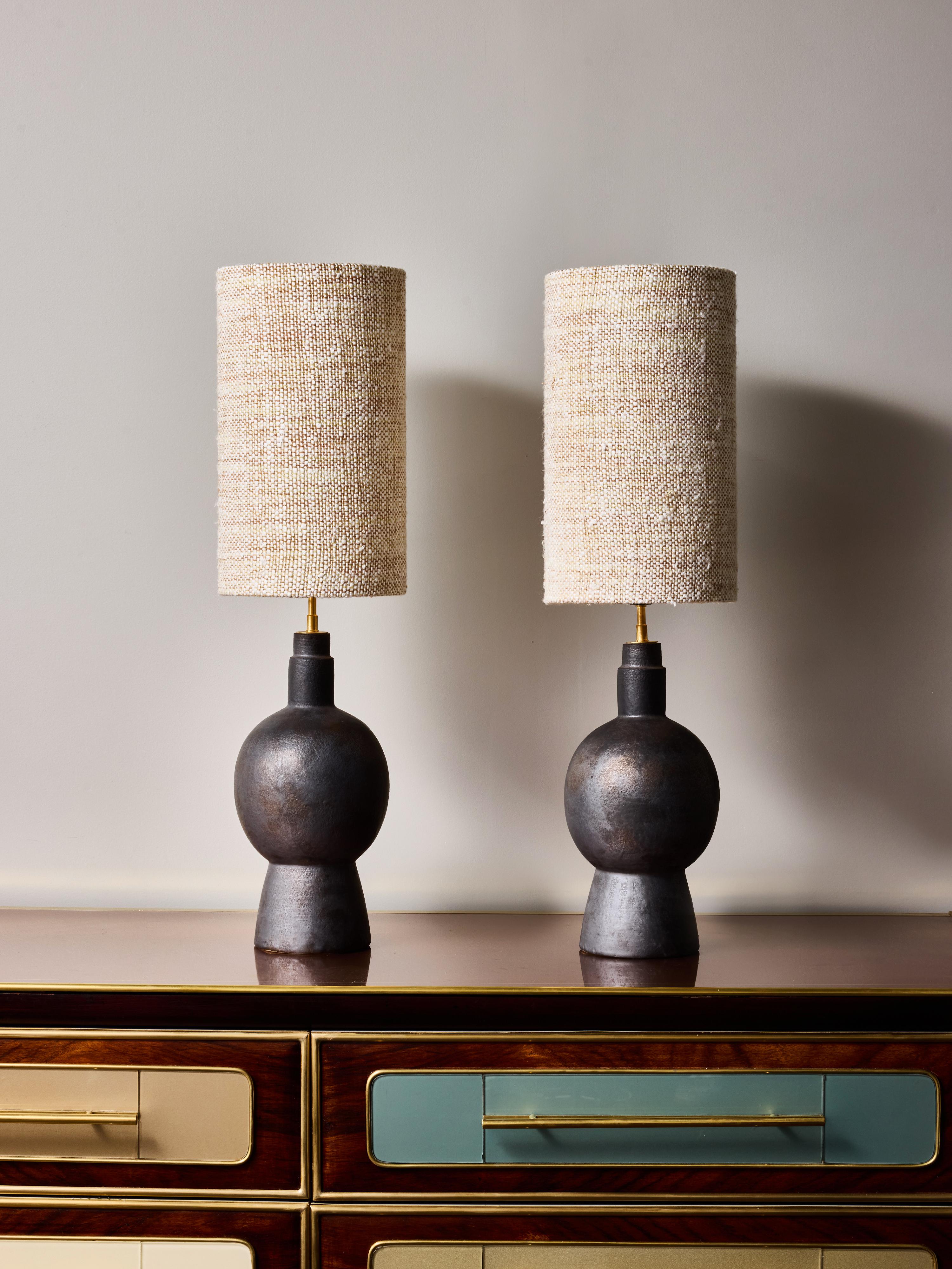 Paire de lampes de table en céramique de l'artiste contemporain français André Bloch. Chaque lampe présente une base sculpturale composée d'une forme sphérique s'élevant d'un piédestal effilé, finie dans une patine riche, sombre et brunie avec de