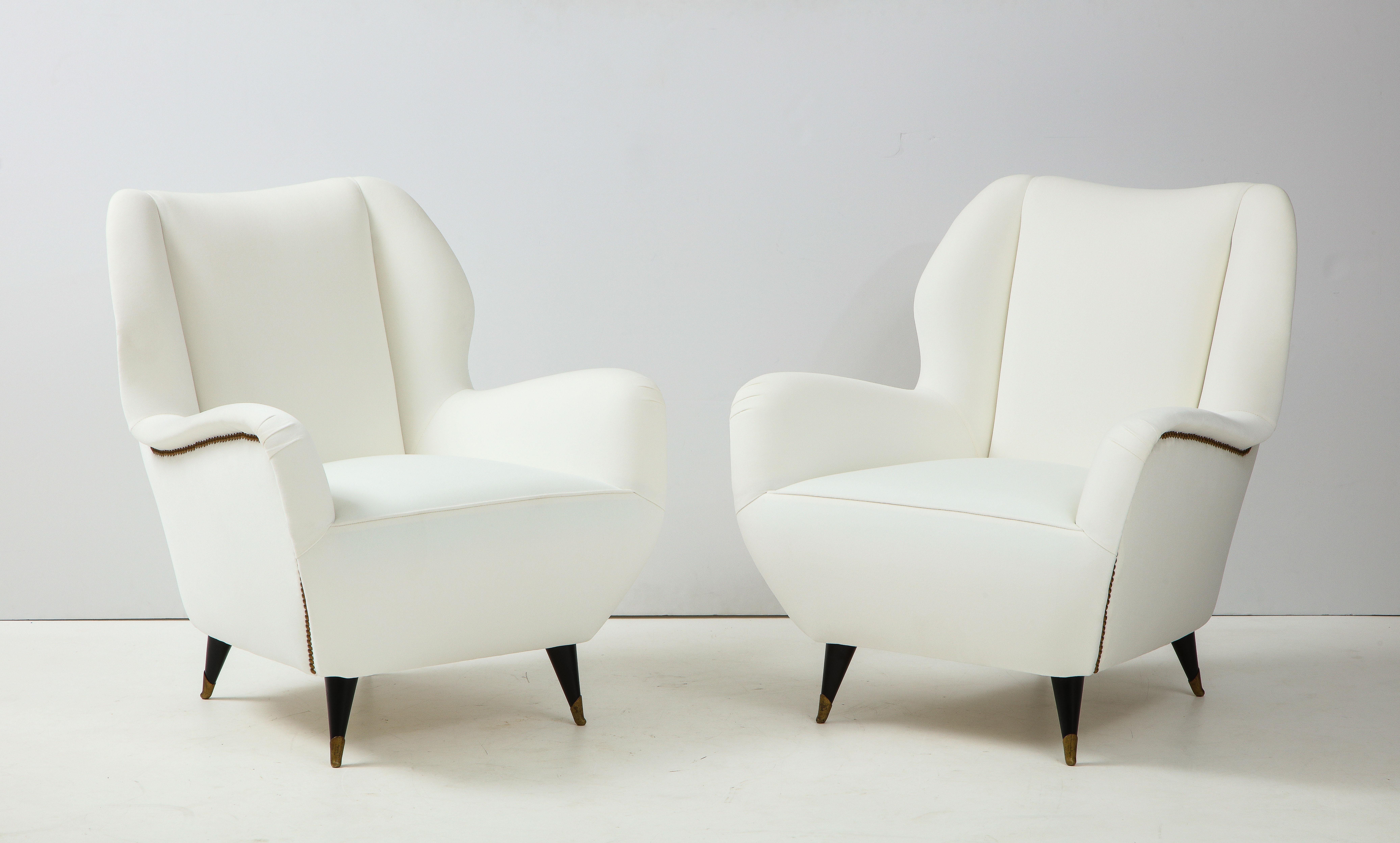 A very elegant pair of Italian vintage mid century modern lounge chairs; their highly sculptural shape is complemented by custom originally designed brass nail heads. Beautifully proportioned with a comfortable and wide seat, the whole is supported