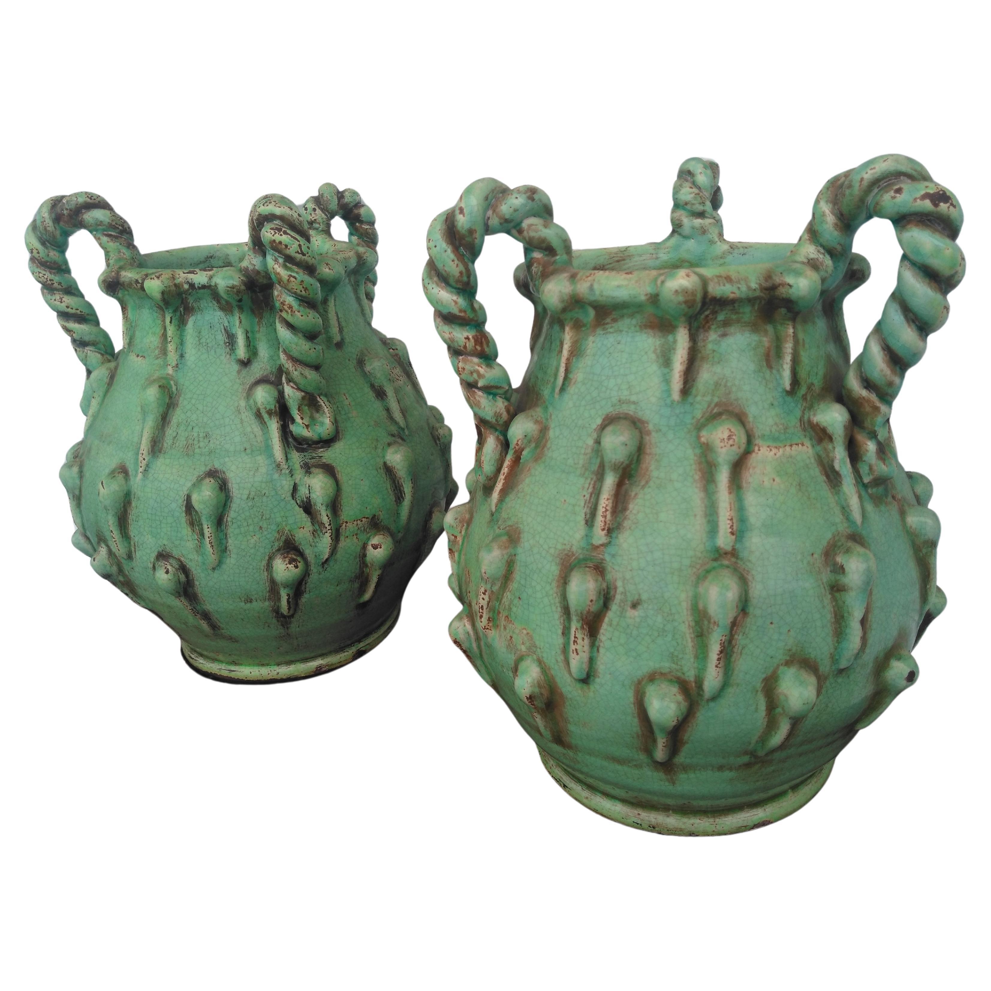 This is a stunning pair of lime green hand crafted vases. They are pottery and have a  artful look. The arms are rope twisted and the sides have a patina like glaze with outward protrusion designs all over.
An interesting design.