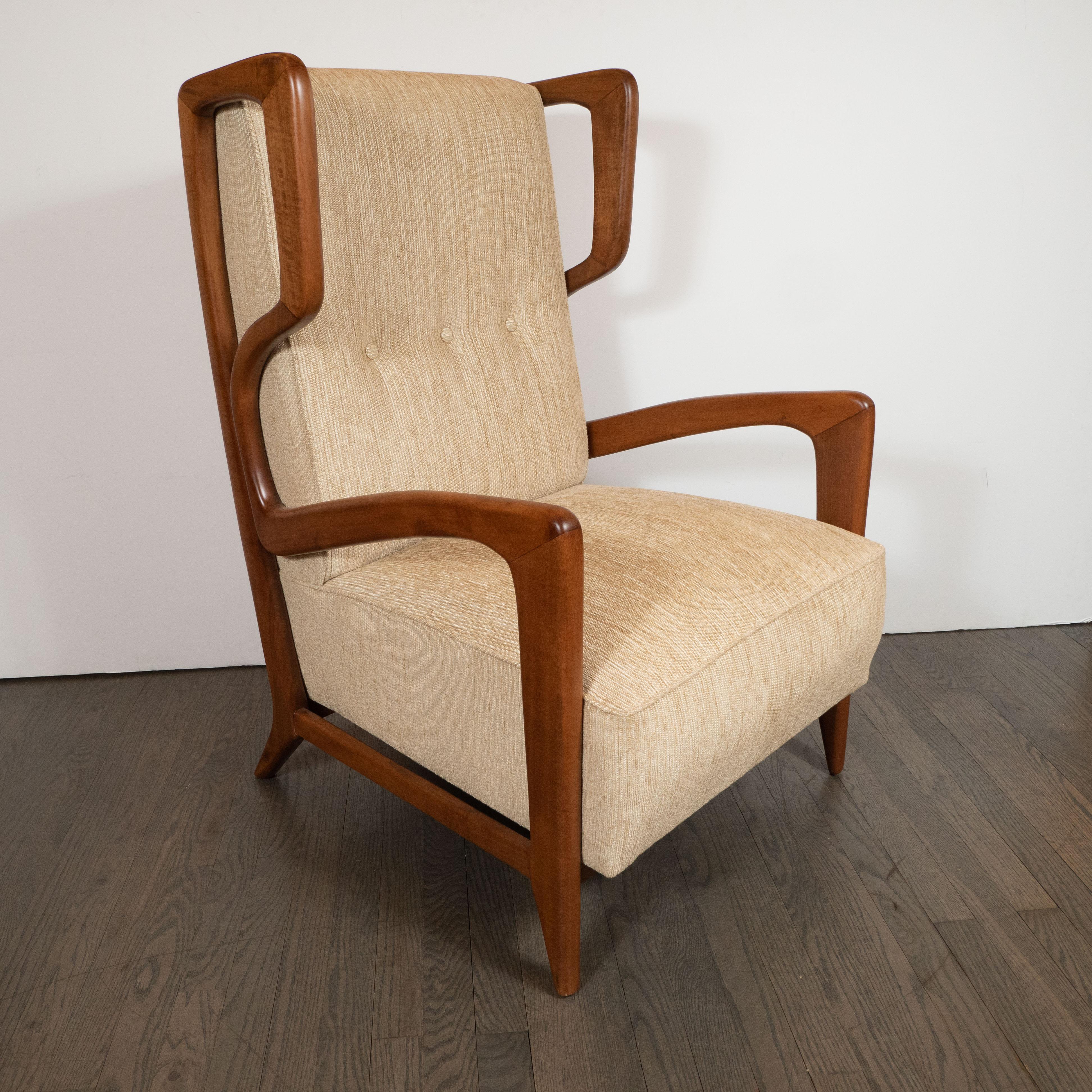 This stunning and sculptural pair of Mid-Century Modern lounge chairs were realized in Italy, circa 1950. They feature high button backs and a wonderfully unusual and highly sculptural frame in handrubbbed walnut- offering a wealth of curvilinear
