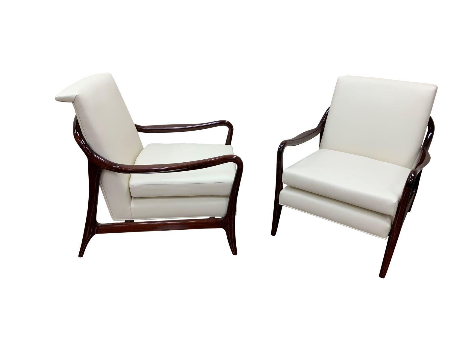 Professionally restored luxurious pair of large scale lounge chairs. Crafted with solid walnut in a high polished finished. Perfectly complimented with a new soft cream upholstery. This particular example I have never seen in my thirty five years of