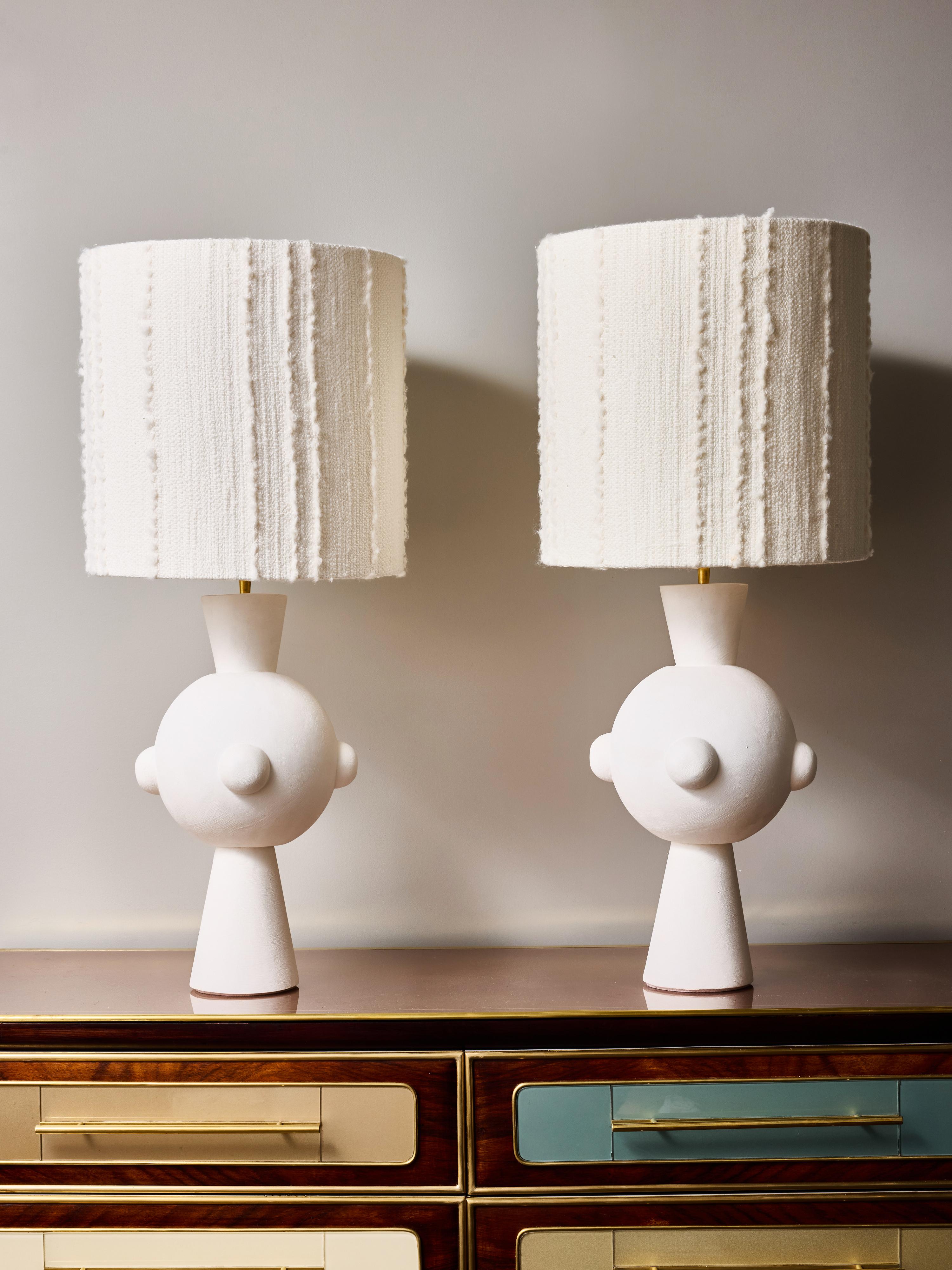 A striking pair of contemporary plaster table lamps distinguished by their bold, sculptural silhouettes. Each lamp features a commanding spherical body punctuated by four rounded protrusions, balanced on a tapered conical base and topped with a