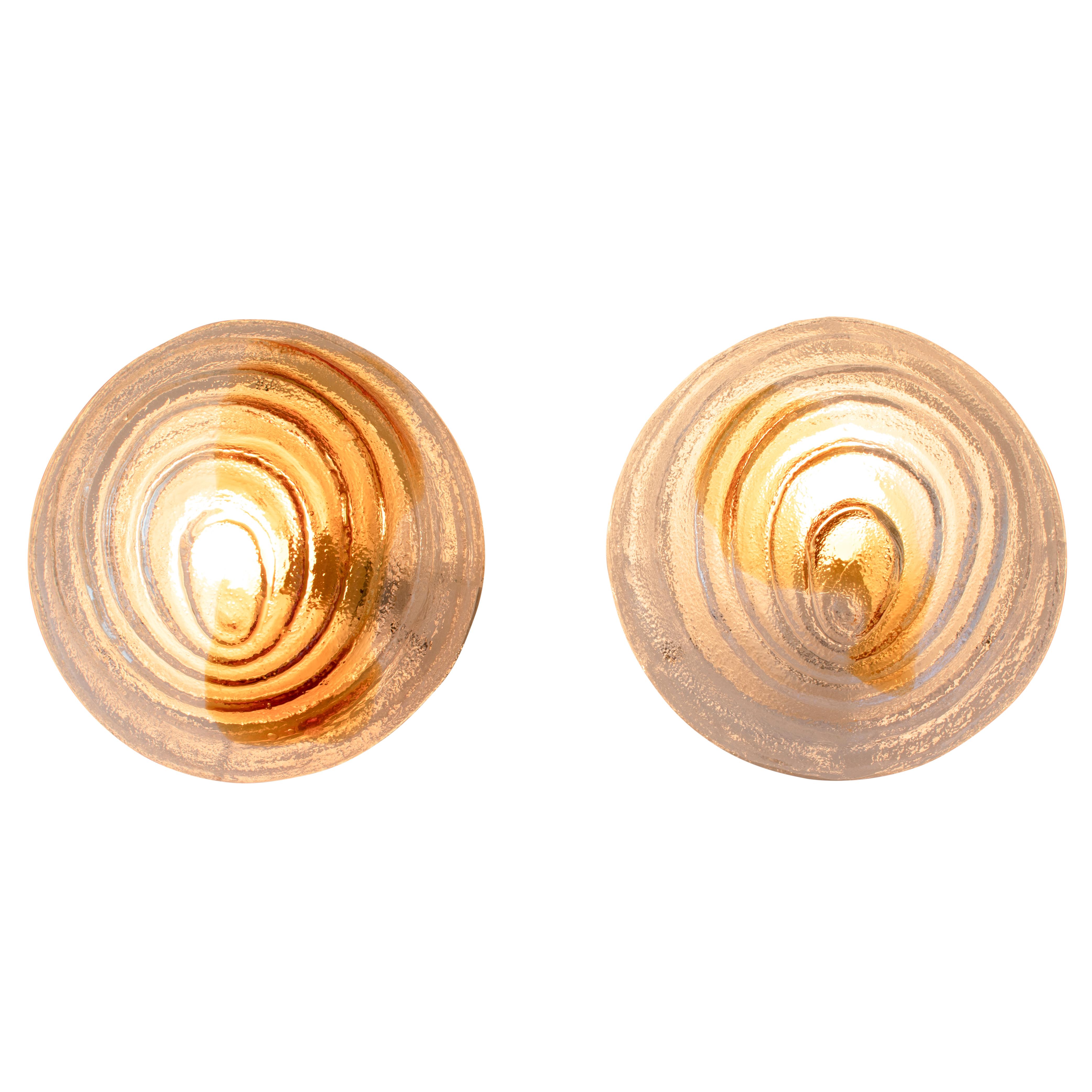 Murano glass sconces feature circular clear glass globes with amber inclusions cast in a highly sculptural swirl design with great depth and texture. Each glass globe attaches with three set screws to a white-painted metal base that holds a single
