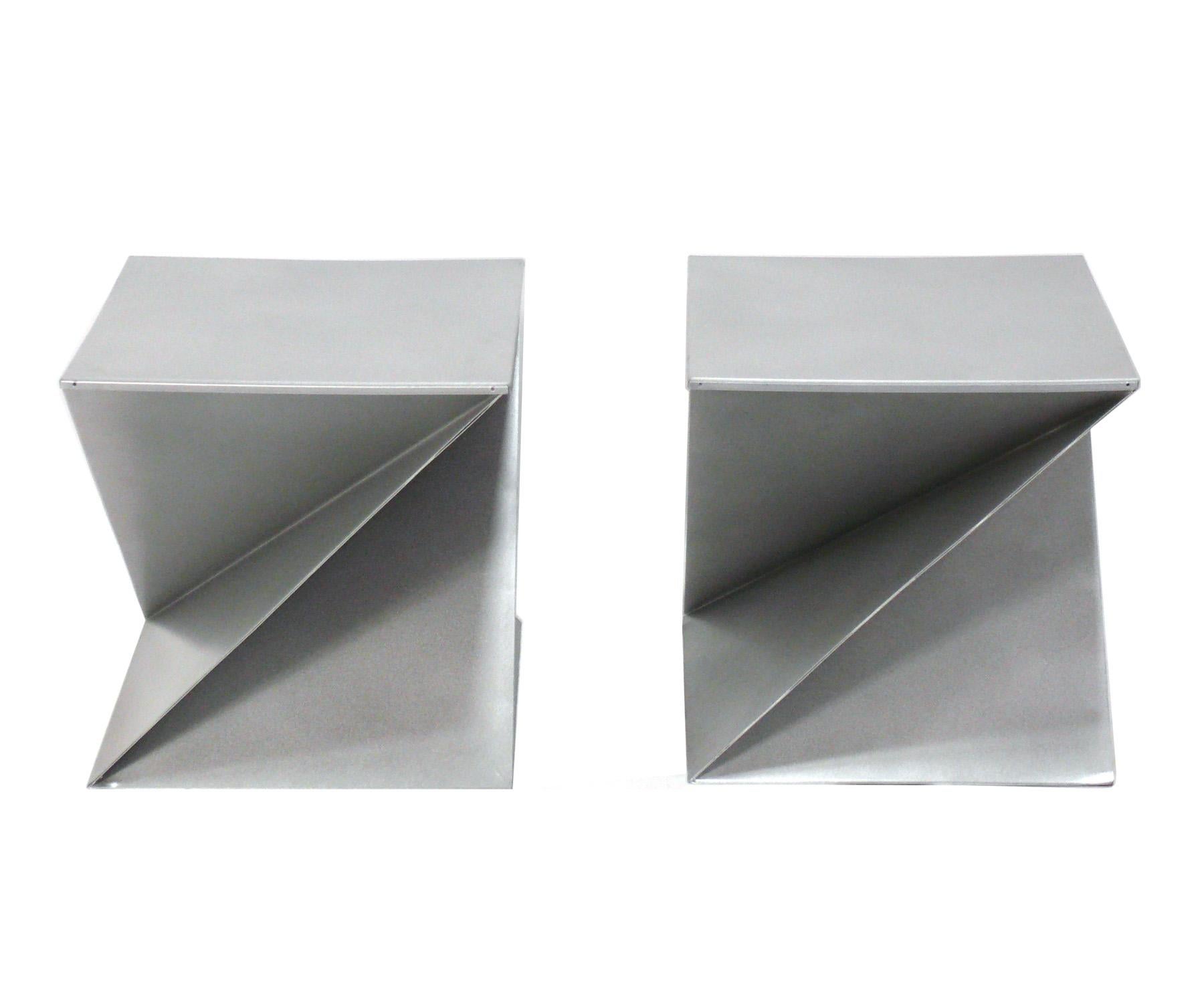 Pair of sculptural origami folded metal end tables, France, circa 1970s. They are constructed of silver enameled metal. The tabletop of each removes to reveal a hidden storage area. They are a versatile size and can be used as end or side tables, or