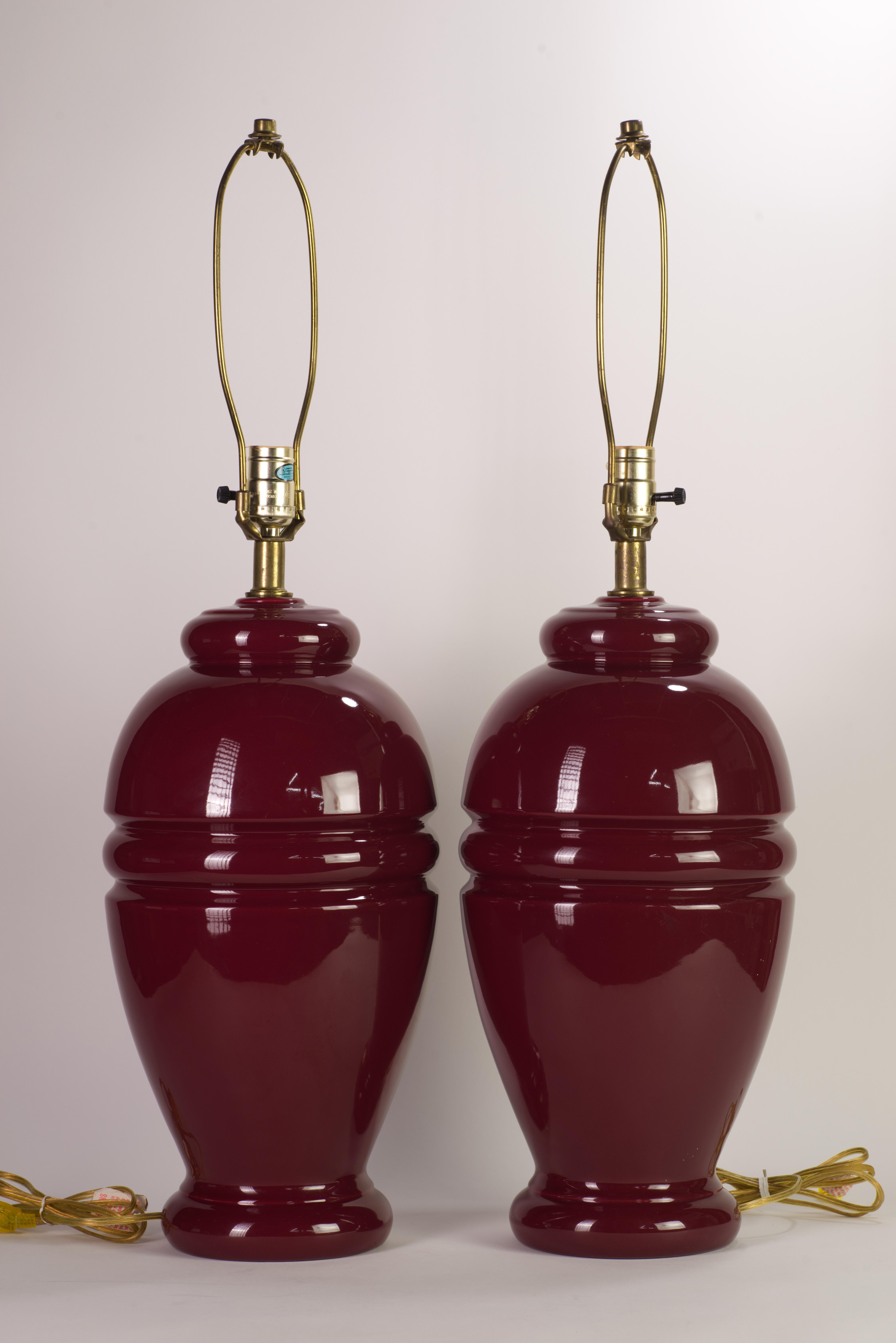  Pair of large, sculptural ceramic lamps with a red burgundy oxblood glaze with brass necks was custom made to order; one of the lamps still retains the manufacturer's sticker with the specs. Rich, saturated color of the glaze elevates minimal, but