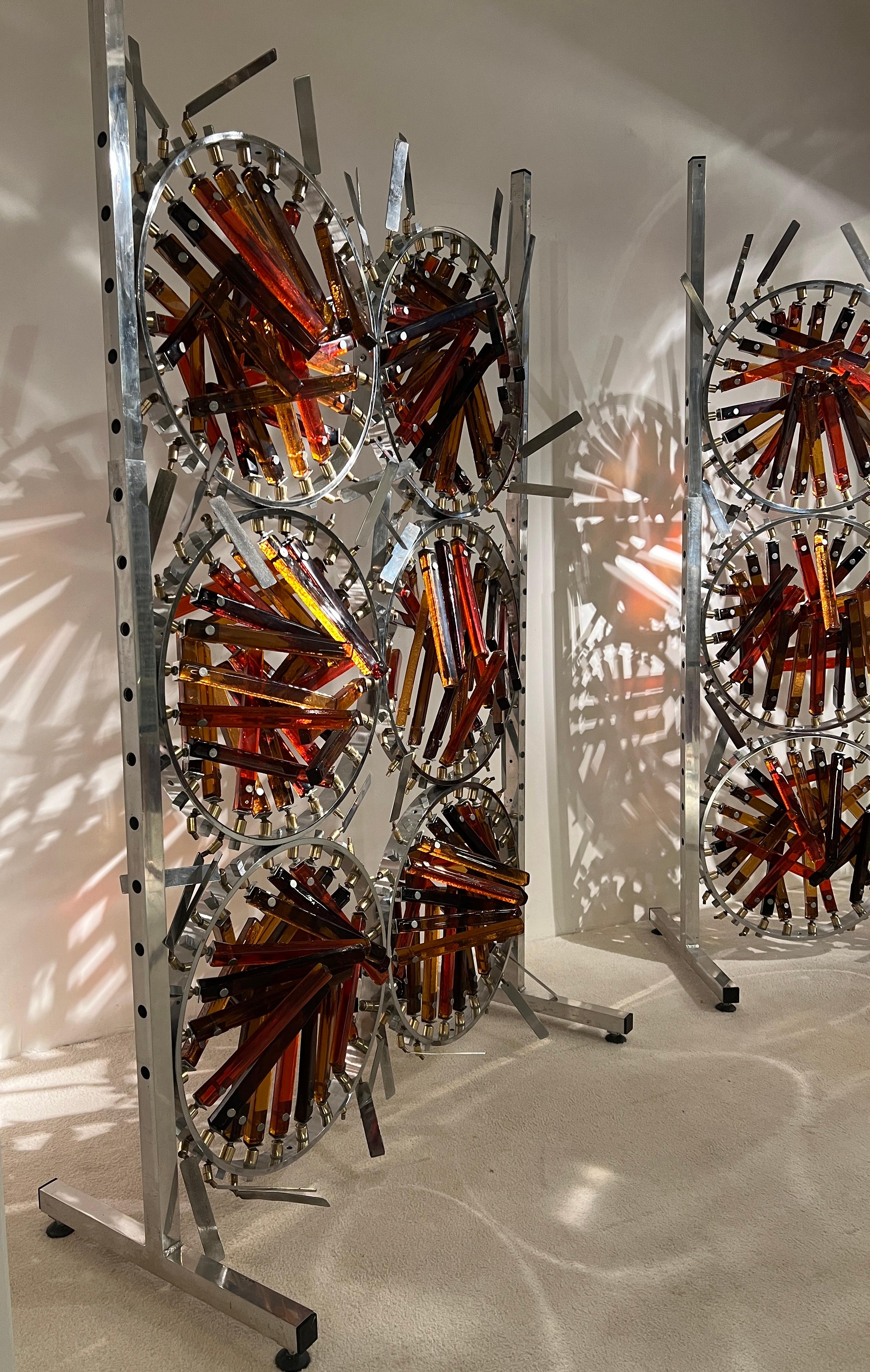 2 Bildschirme aus Stahl und Glas von Marcello Avenali (1912-1981). 
Die skulpturalen Elemente wurden für eine Installation in der Banco Santo Spirito in Rom geschaffen.
Kreisförmiges Stahlband, außen mit 12 Messingstützen, an denen verstellbare