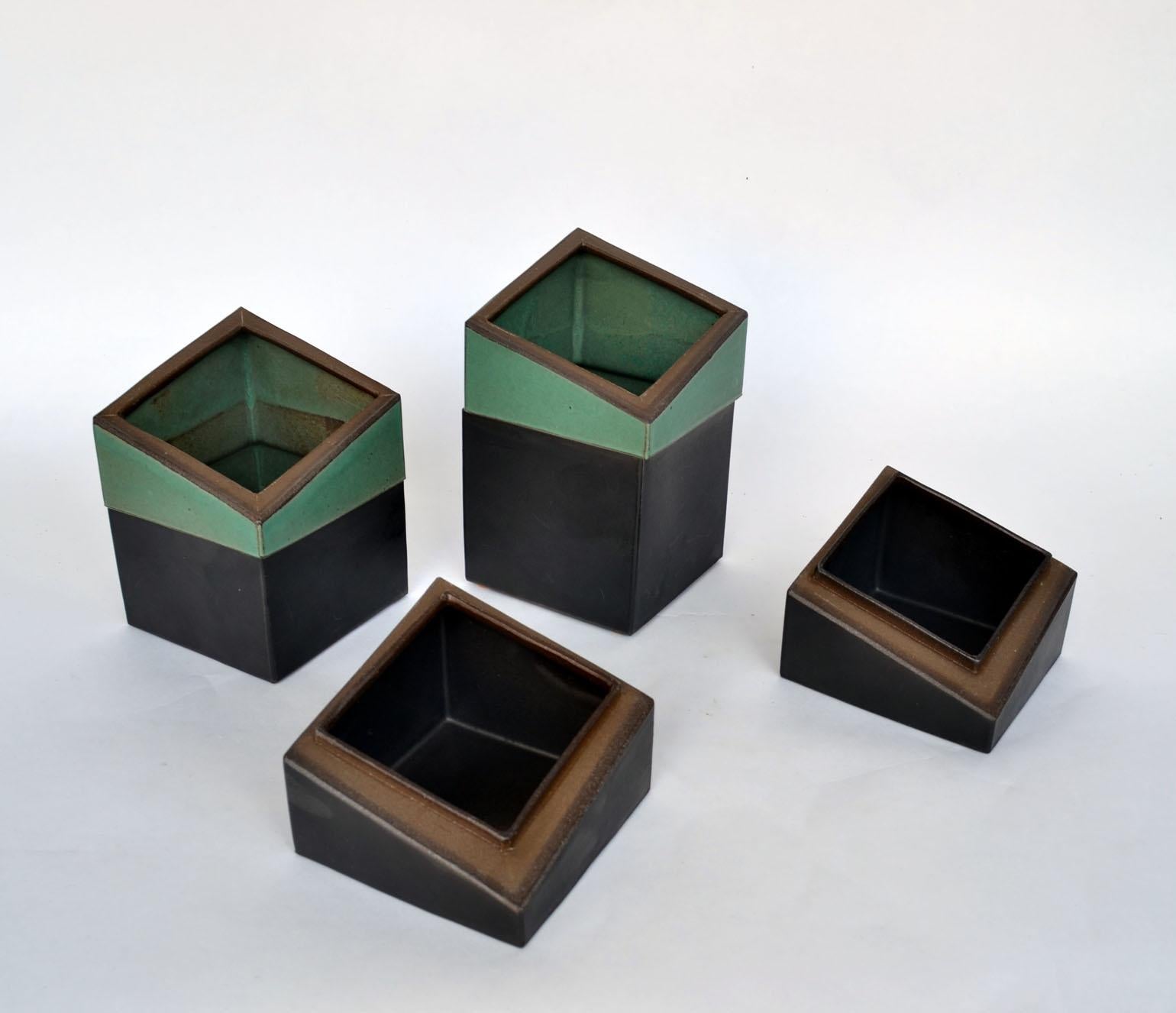 Sculptural square studio pottery boxes, signed PS. The geometric design is emphasised by the alternating green and black glazed sections. The lids fit precisely on the bases of the late 20th century stoneware boxes.

Dimensions:
18.5 x 10 x 10