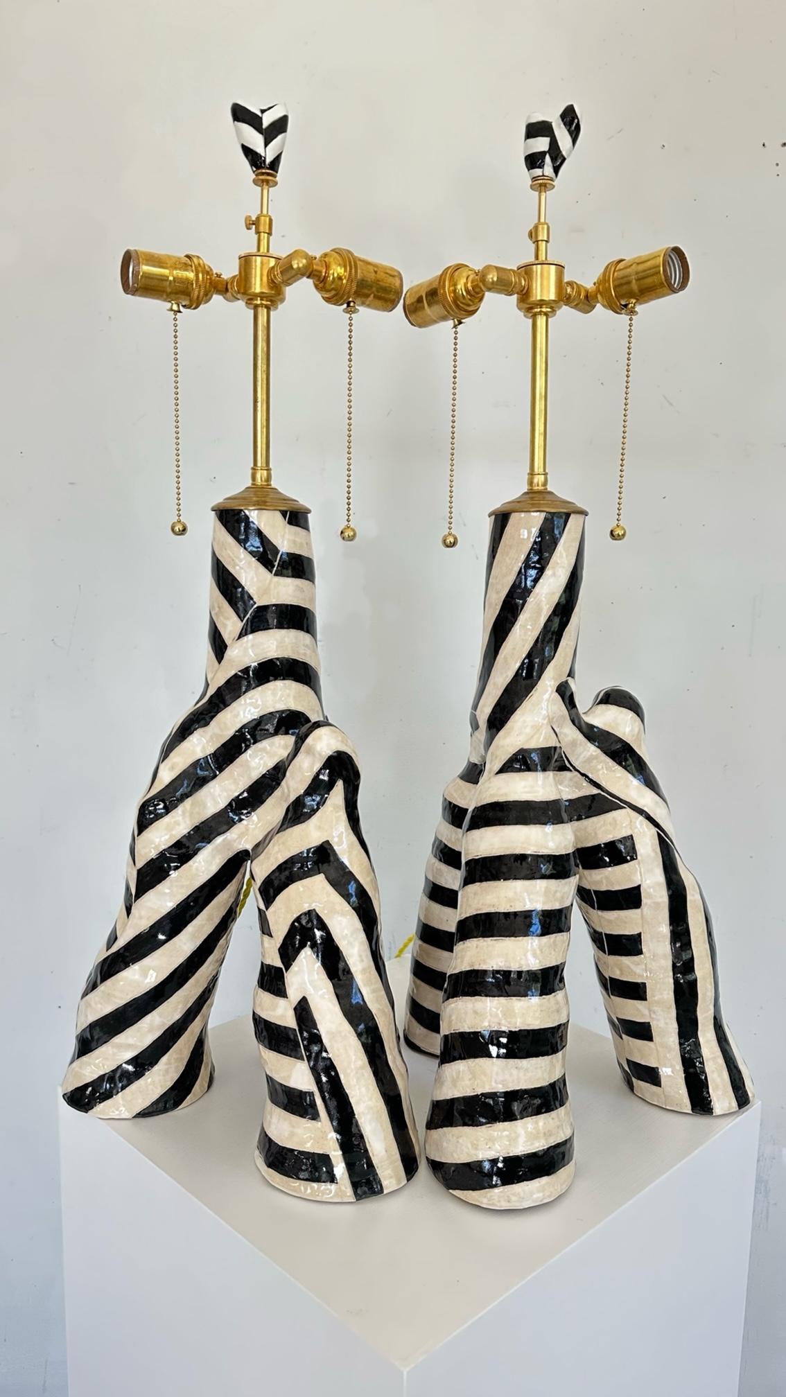 Coppia di lampade da tavolo scultoree in bianco e nero. 

Ispirate all'effetto mimetico dei motivi sulla forma tridimensionale, queste strisce che si intersecano oscurano il senso della forma, creando movimento e illusione nella forma a tre