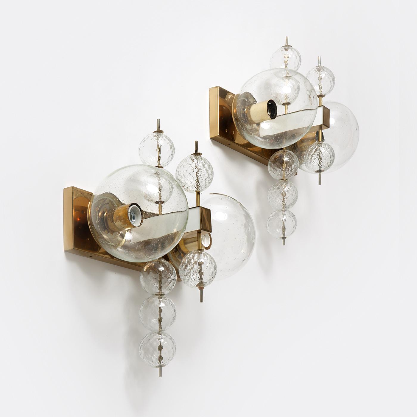 Rare pair of sculptural wall lamps in brass and glass, manufactured by Kamenický Šenov in former Czechoslovakia, 1970s.

These wall lamps have a magnificent sculptural design. Each lamp features a central brass fixture that holds two large glass