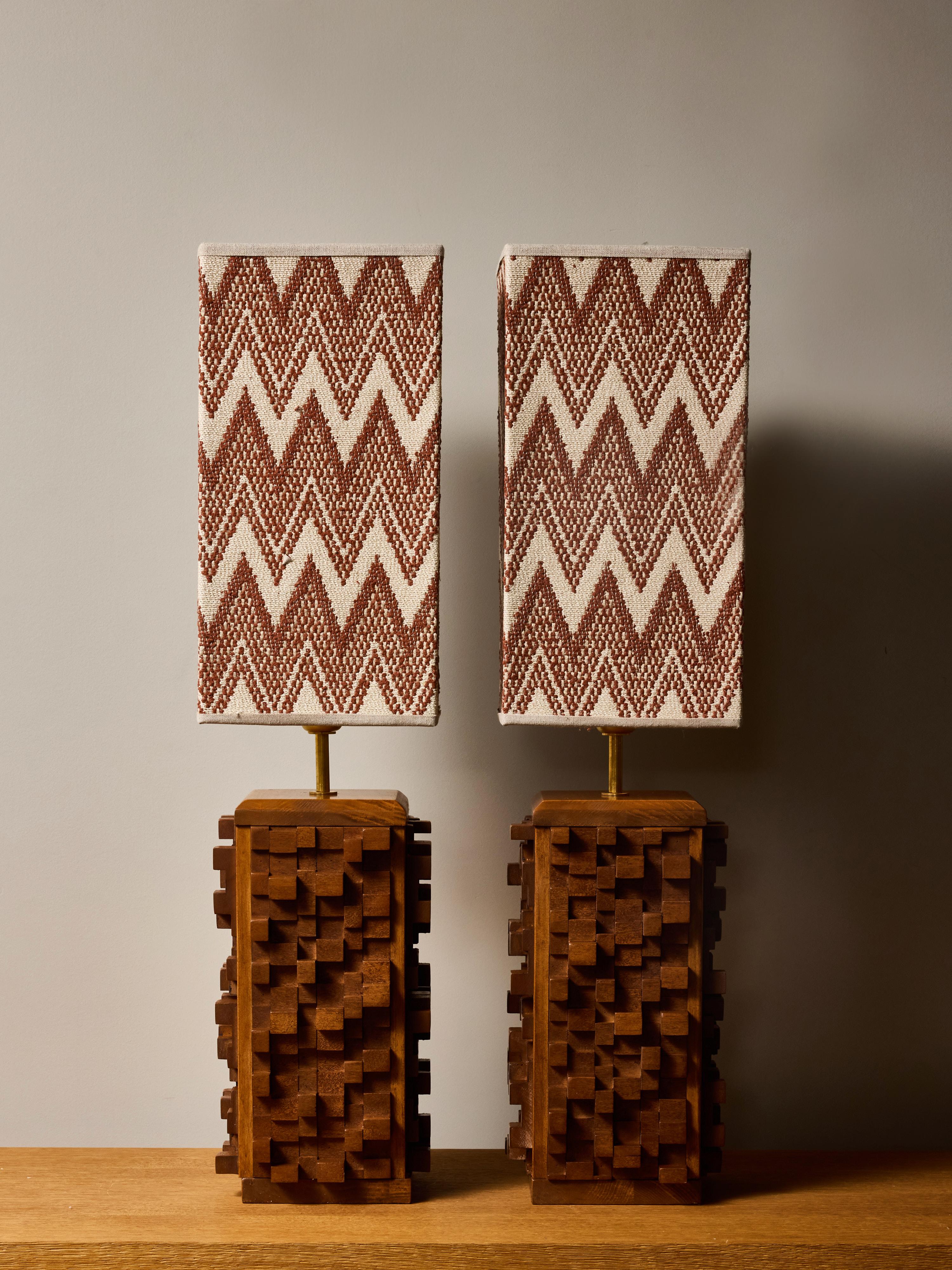 Striking pair of contemporary sculptural table lamps, each featuring a meticulously hand-carved wooden base composed of interlocking cubic forms. The relief pattern creates a dynamic three-dimensional façade, producing shifting light and shadow that
