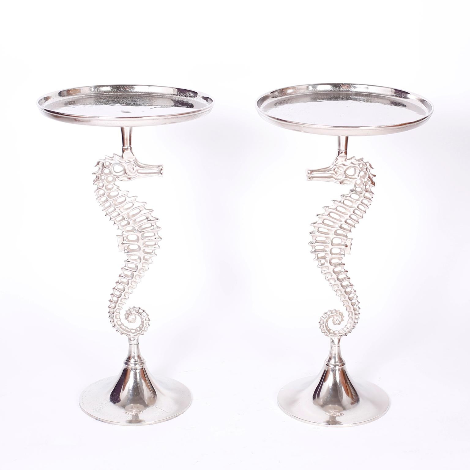 Pair of mid century stands or tables crafted in aluminum with a turned tray on the top supported by a seahorse with a stylized modern form on a turned round base.