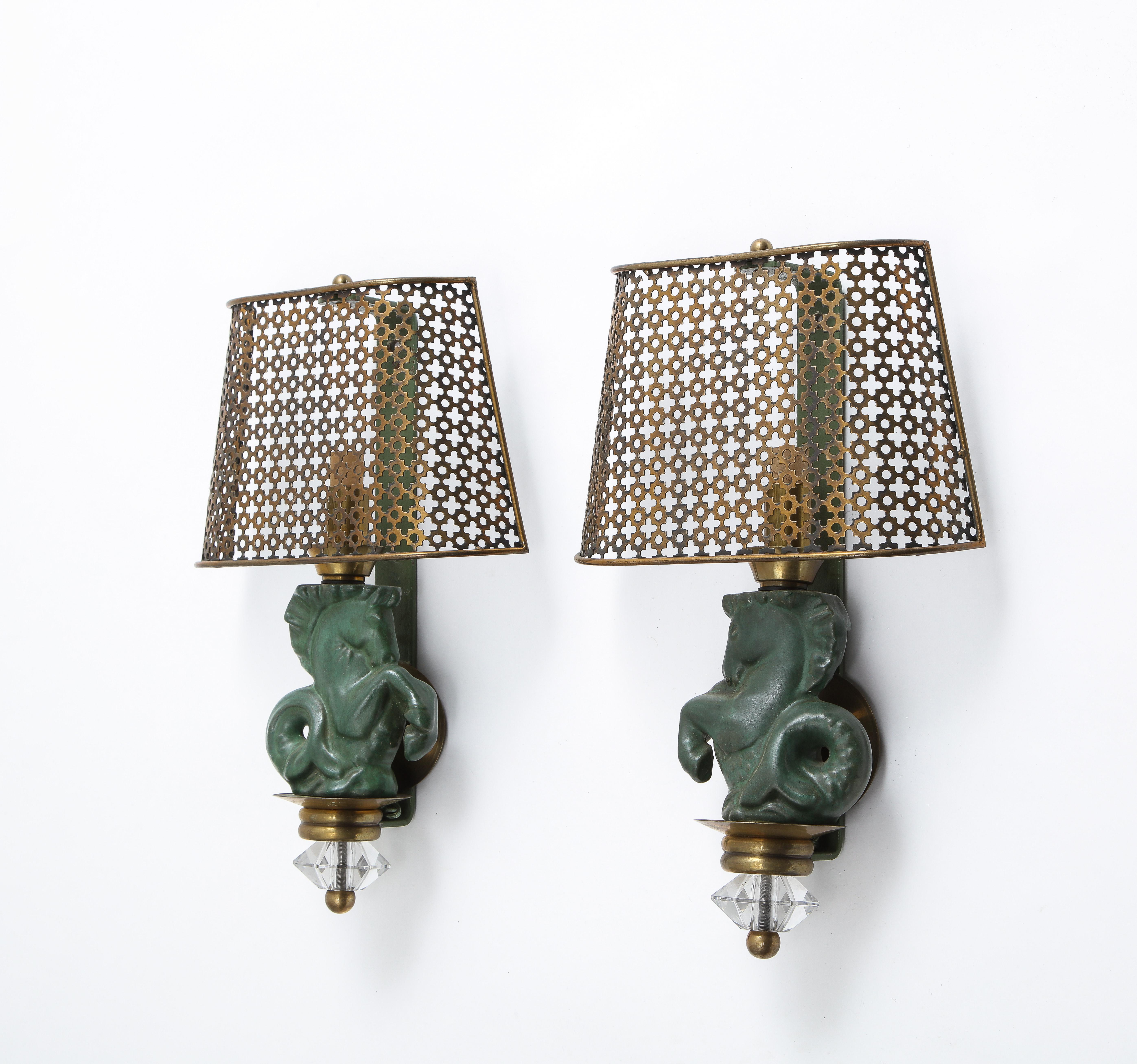 Elegant pair of ceramic seahorse sconces, the horse motif is in green glazed bisque on metal frames with clover pierced brass shades and a glass and brass finial. Rewired.