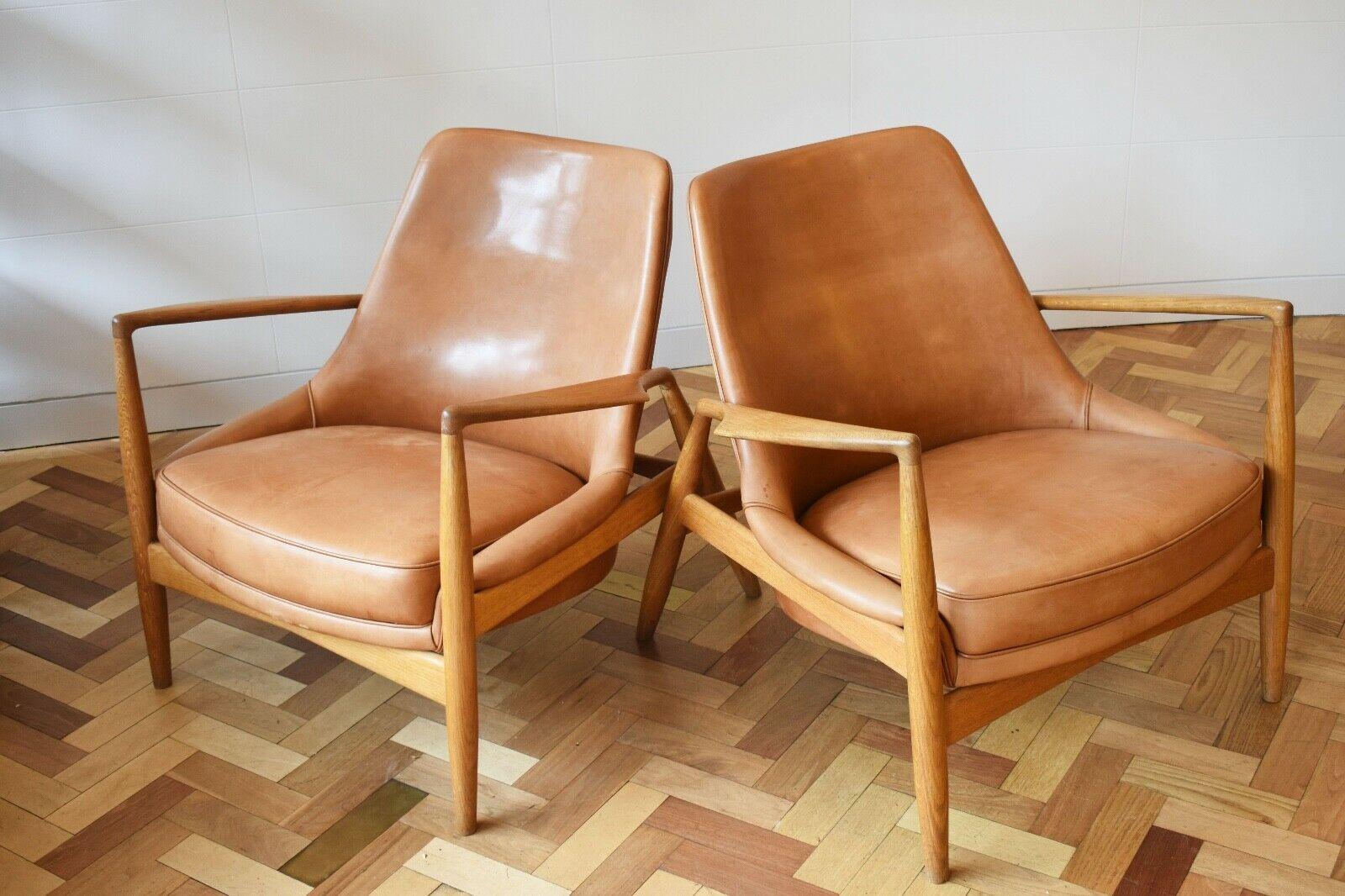 A pair of very stylish Ib Kofod-Larsen ‘Seal’ lounge chairs produced by Brdr Petersens Polster Mobelfabrik with cognac coloured leather seats and oak frames. 

Manufacturer’s label to underside of the seats. 

The seal chairs received