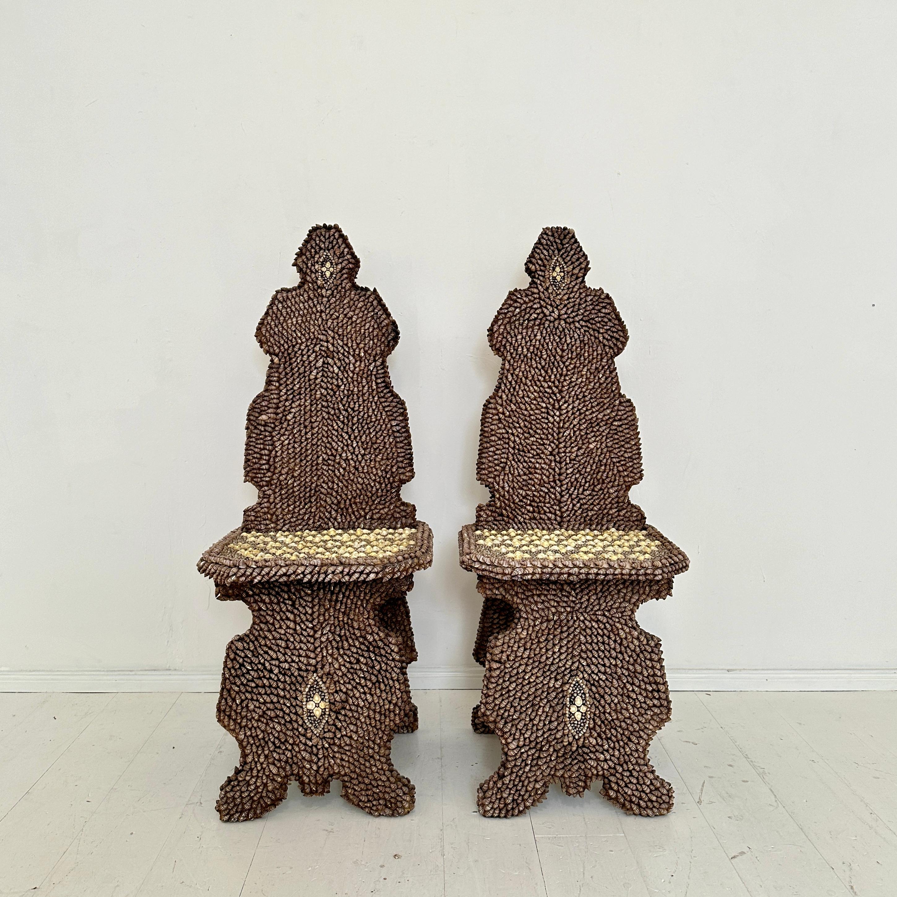 Evoking a whimsical, nautical fantasy, this pair of seashell-encrusted chairs by J. Antony Redmile, crafted in the United Kingdom around 1970, represent the pinnacle of decorative art. Every surface is meticulously covered in a breathtaking mosaic