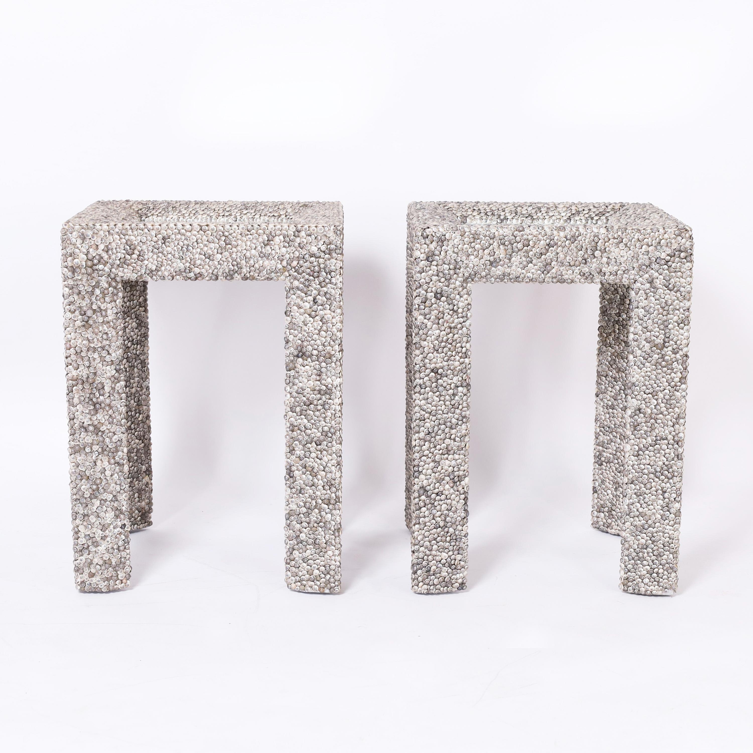 Chic pair of stands crafted in wood in parsons style with an inset mirror in the top and entirely covered in thousands of organic seashells. Signed by Currey & Company on the bottoms.